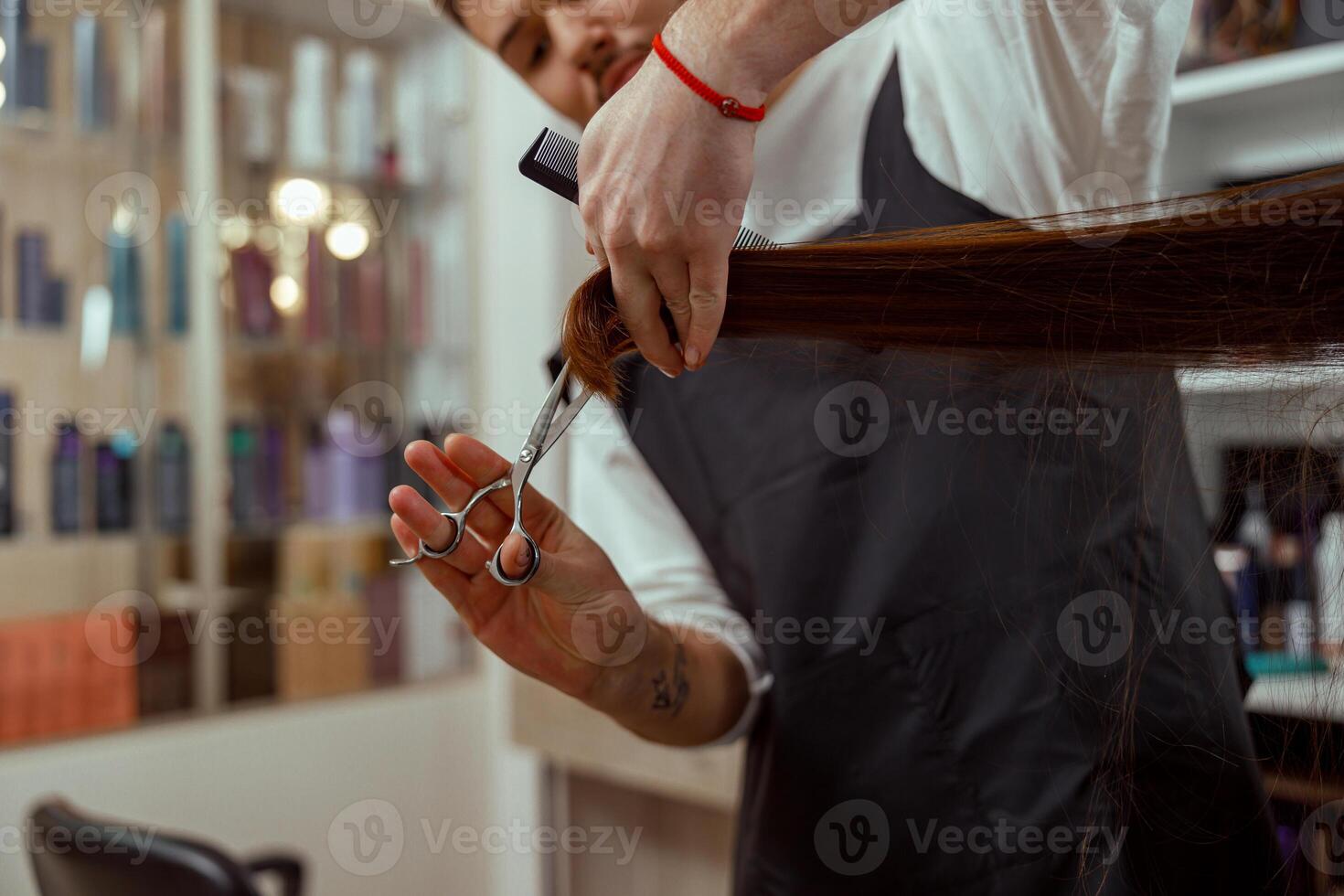 Closeup of hairdresser hands holding a comb while cutting hair of woman photo