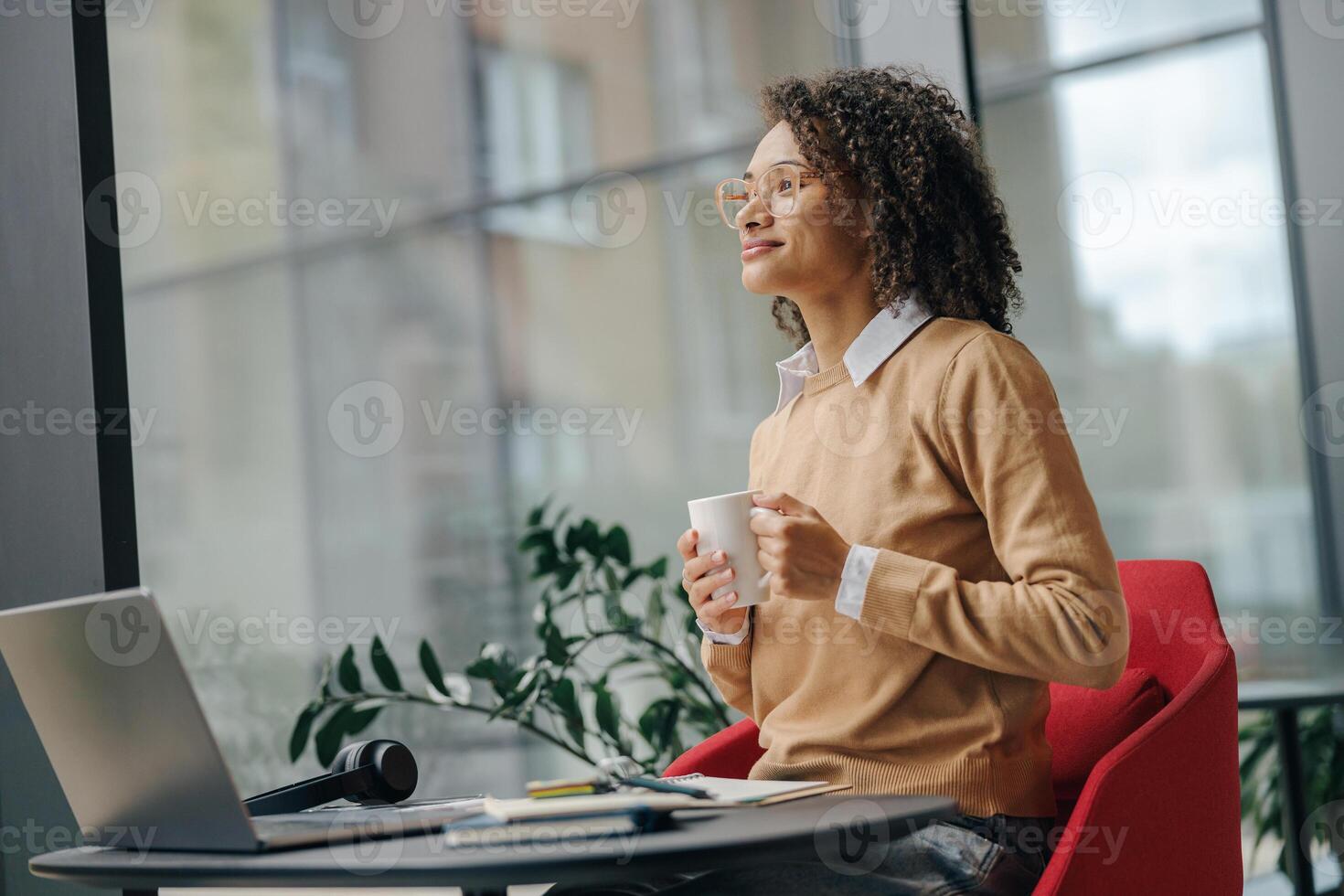 Smiling business woman in eyeglasses have a coffee break during working on laptop in cozy cafe photo
