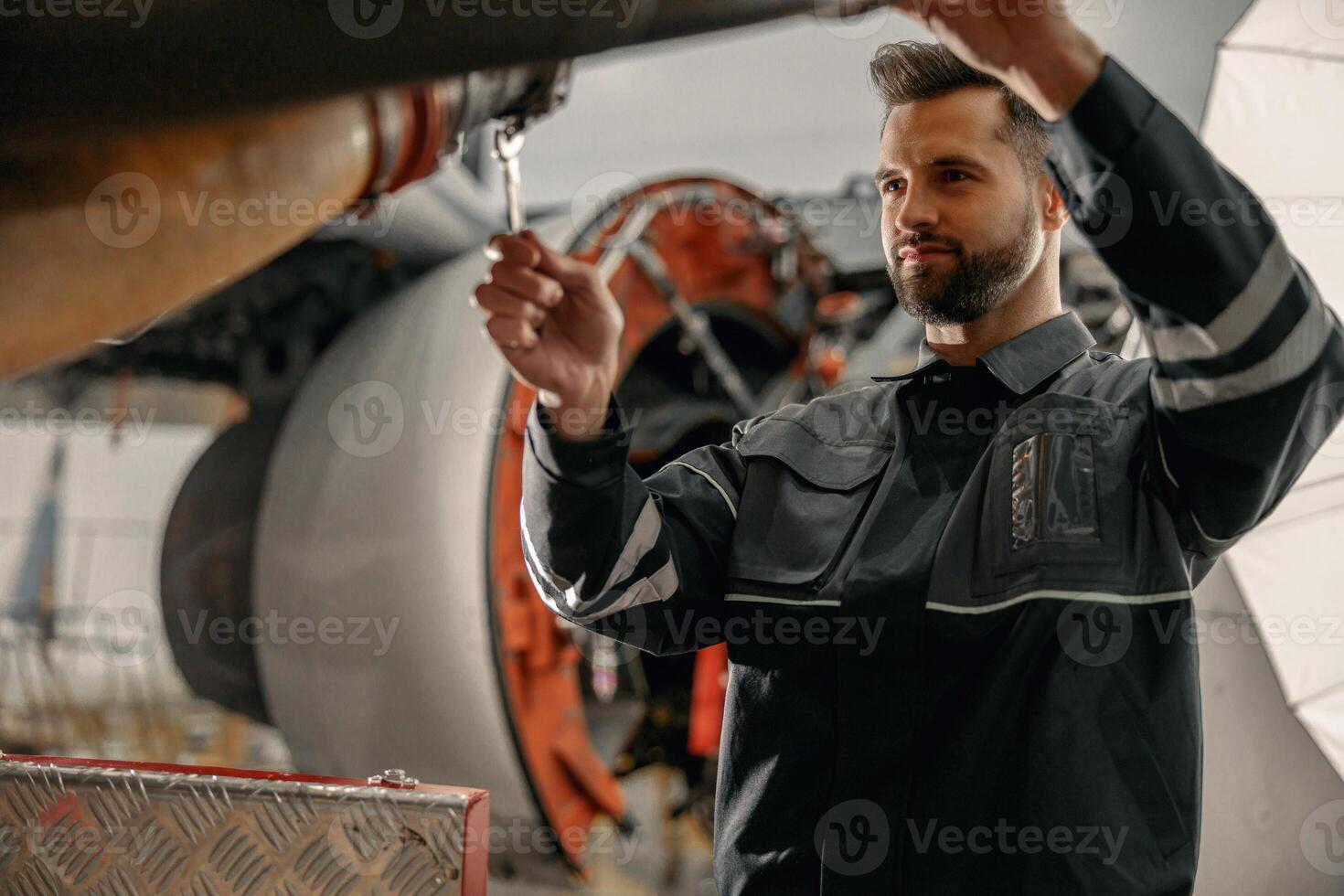 Male aviation mechanic repairing airplane in hangar photo