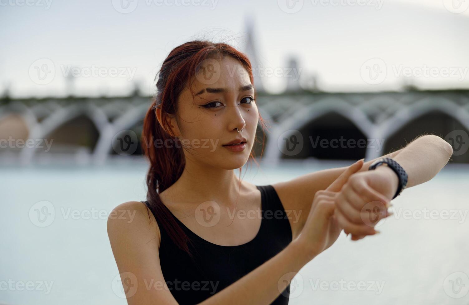 joven mujer en ropa de deporte mirando en reloj inteligente antes de haciendo ejercicio al aire libre Deportes en el Mañana foto