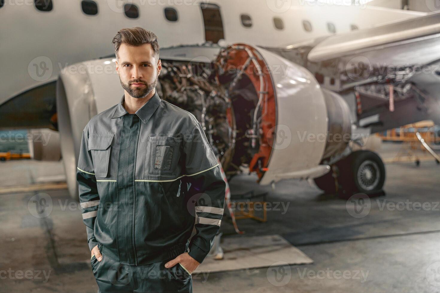 Male airline mechanic standing near aircraft in hangar photo