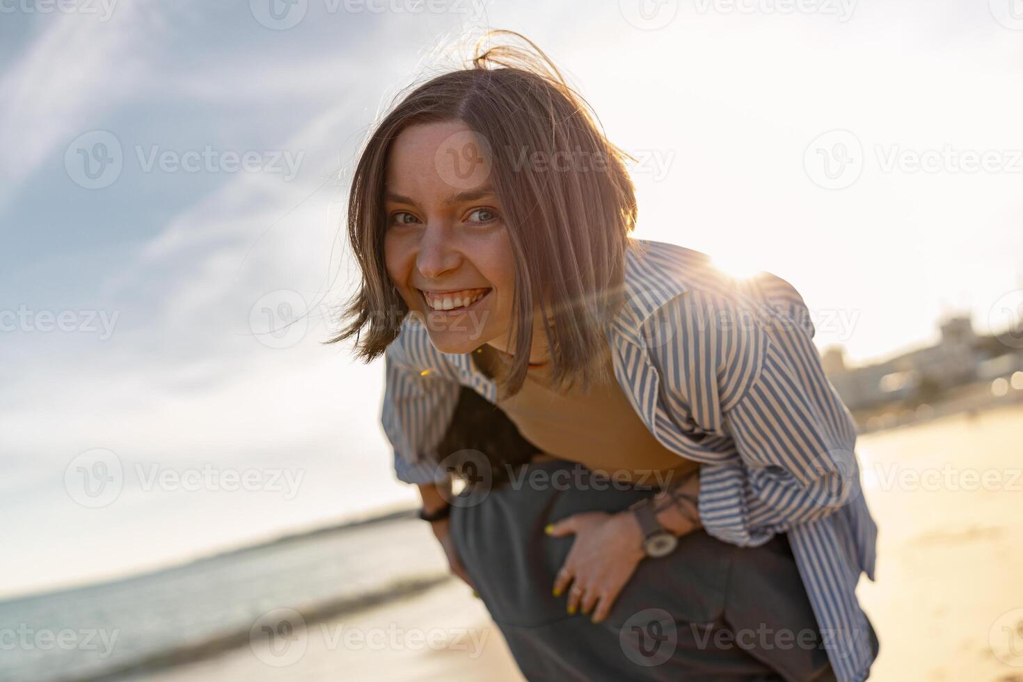 cerca arriba de sonriendo Pareja en amor tonto alrededor mientras caminando a lo largo el playa en soleado Ventoso día foto