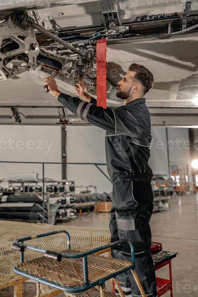 Male aviation mechanic repairing airplane at repair station photo