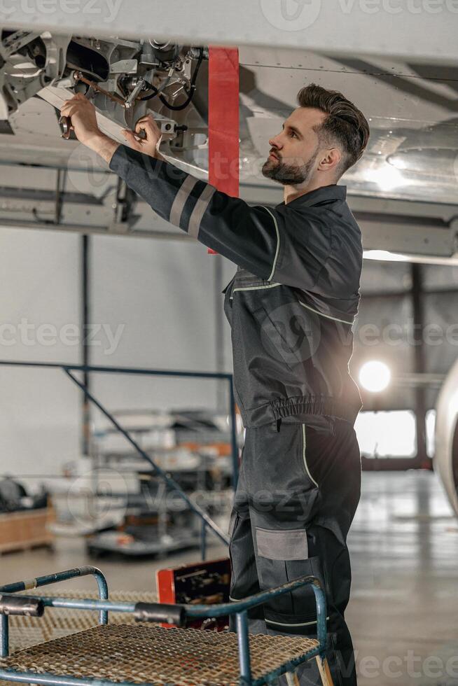 Male aviation mechanic repairing aircraft at repair station photo