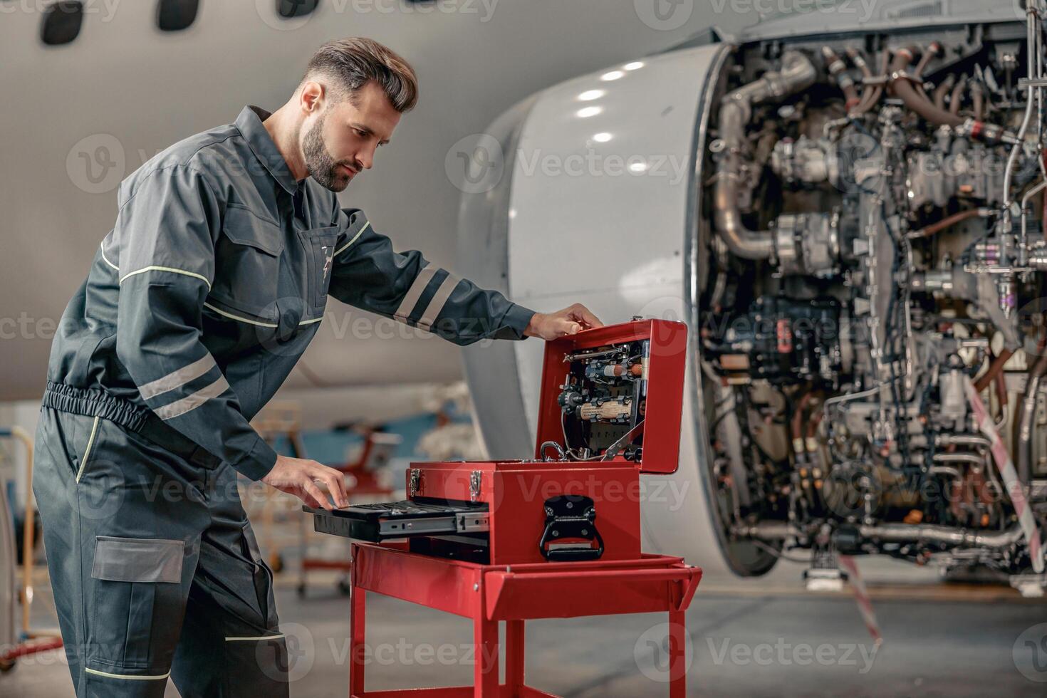 Male airline mechanic working in aircraft hangar photo