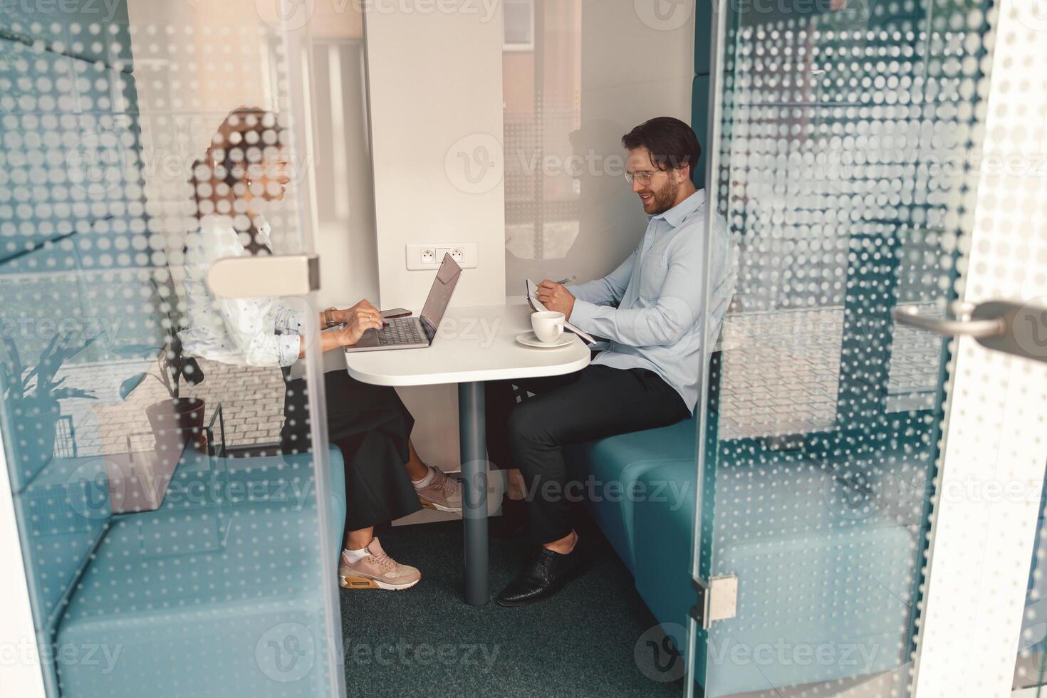 Two diverse business colleagues working together on project sitting in modern meeting room photo