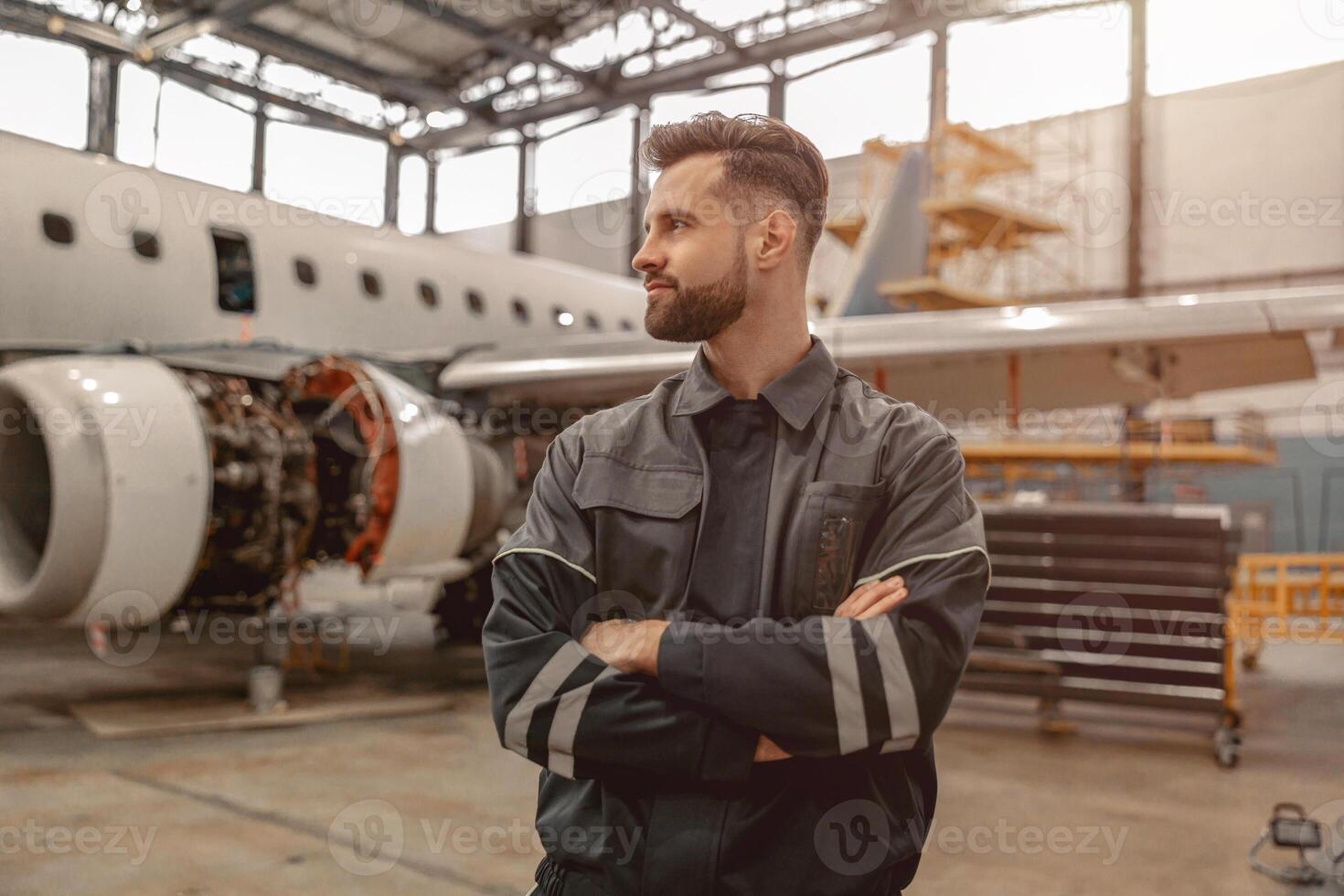 Bearded man aviation mechanic standing in hangar photo