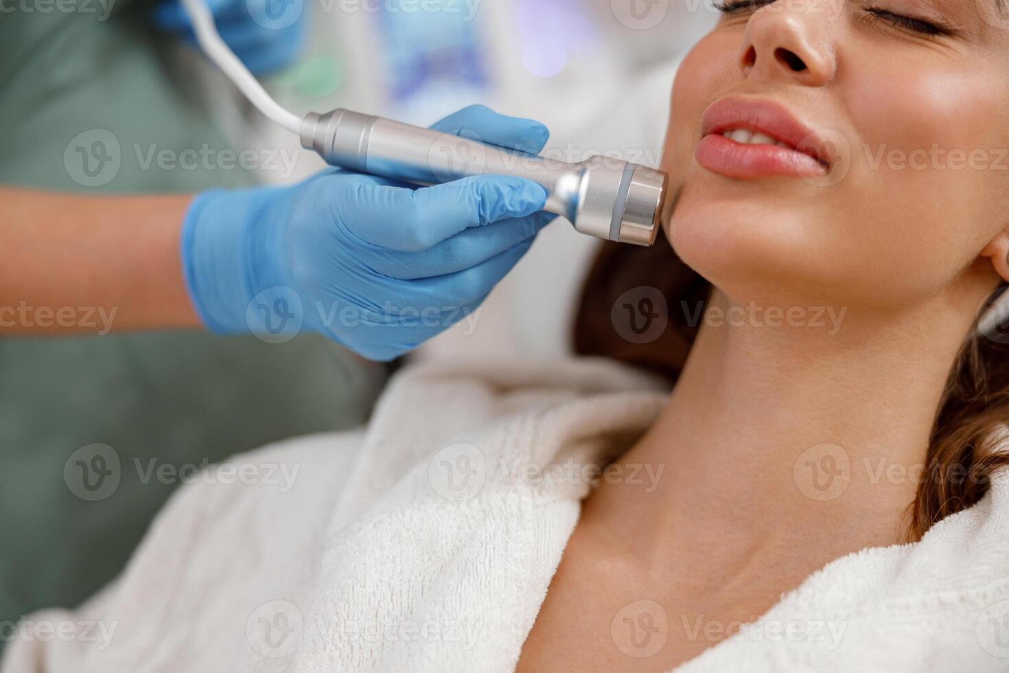 Close up potrait of female client getting aesthetic face skin treatment in beauty salon photo