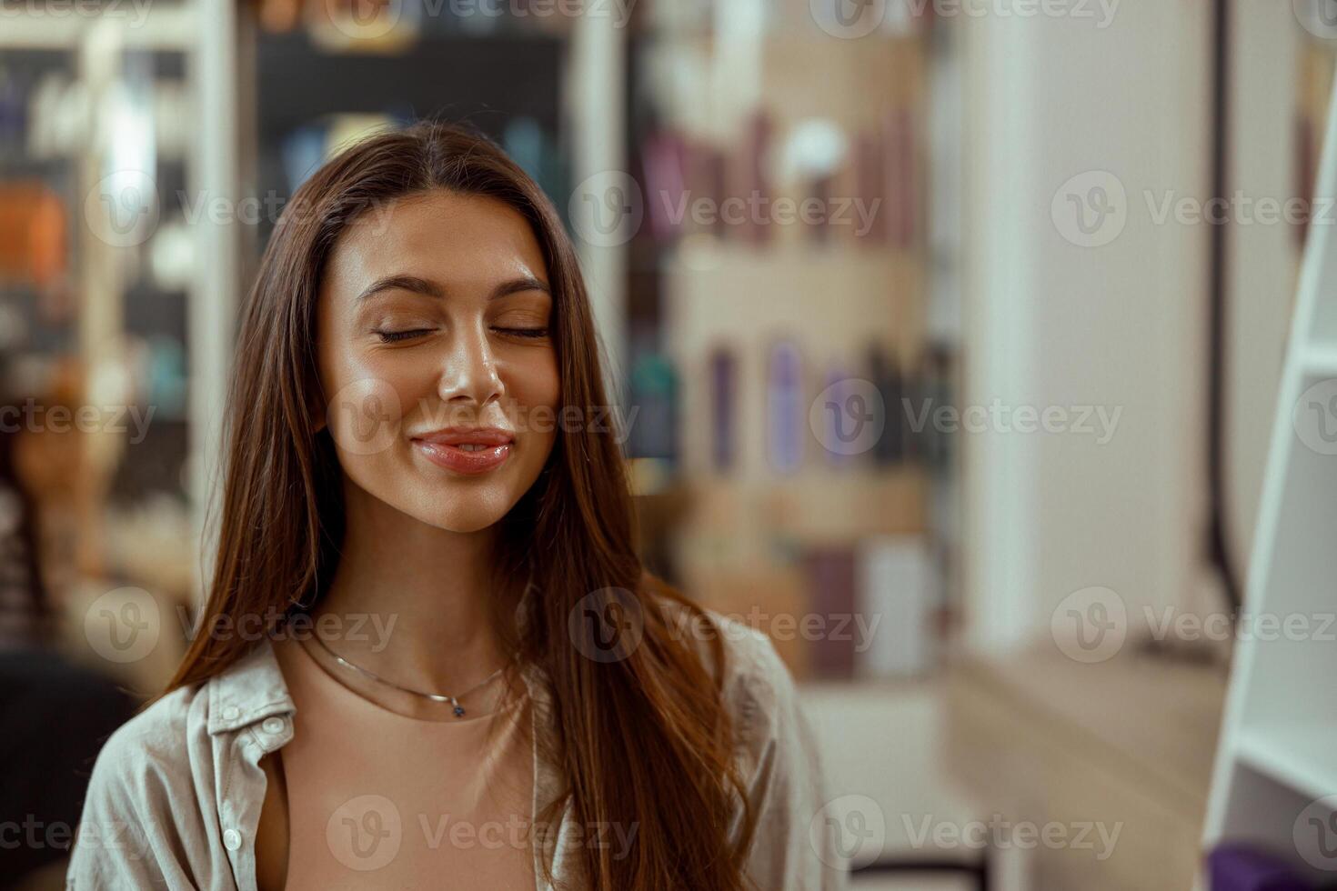 Female client smiling with her eyes closed while getting makeup from professional makeup artist photo