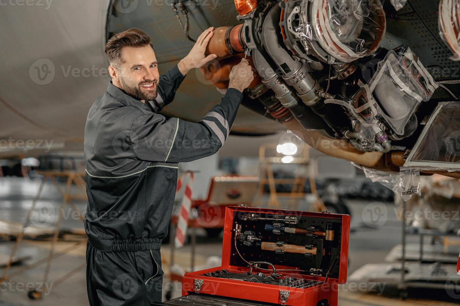 Joyful male mechanic repairing aircraft in hangar photo