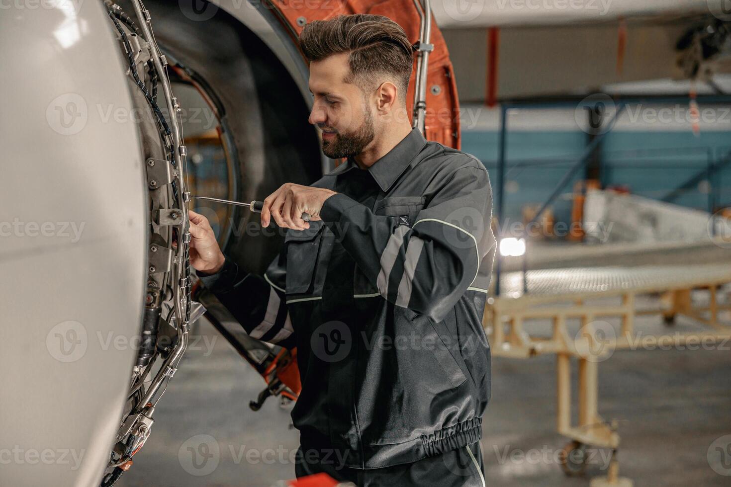 Male aviation mechanic repairing aircraft in hangar photo