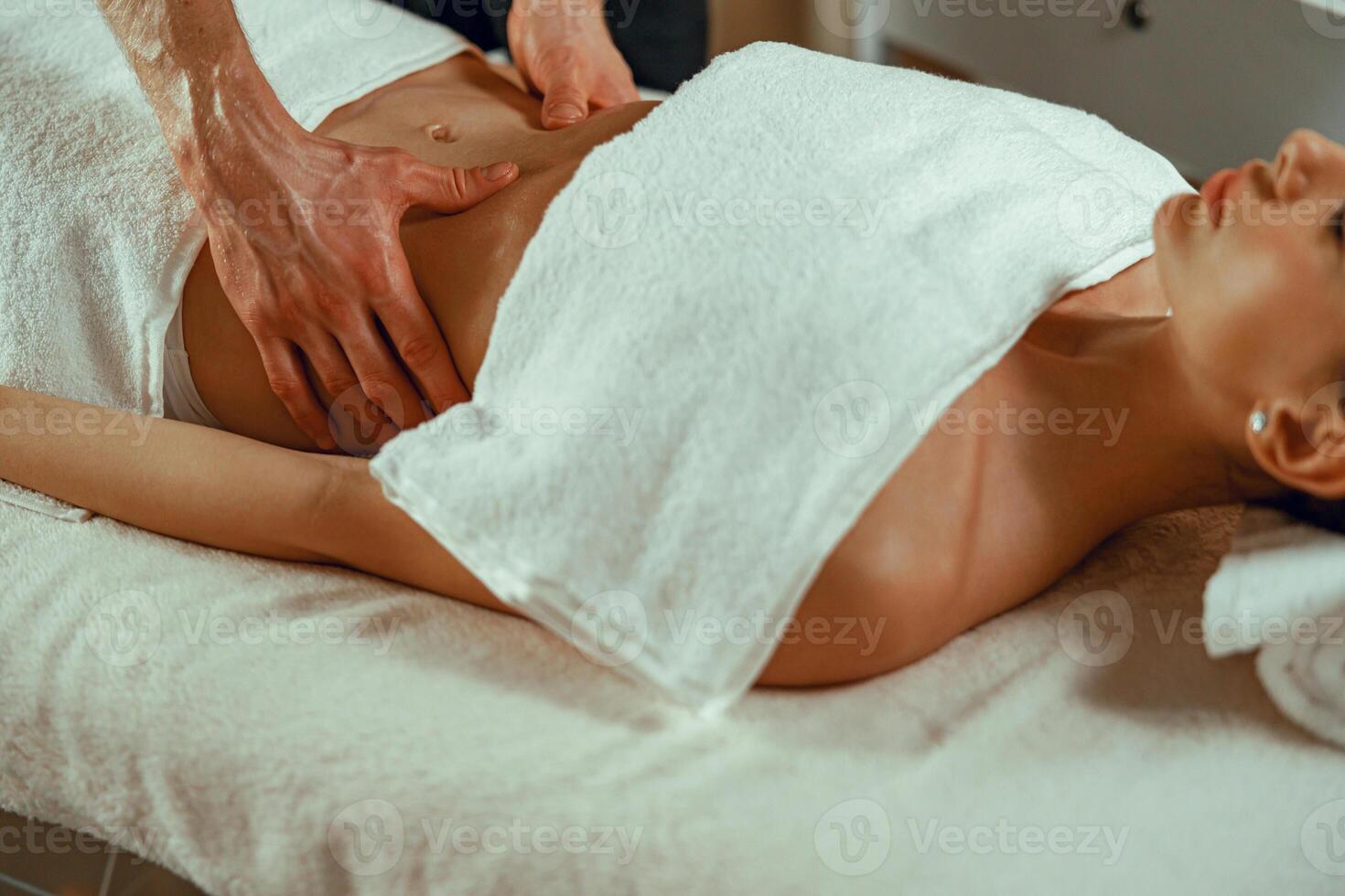 Female client getting relaxing massage, lying on a daybed at spa salon photo