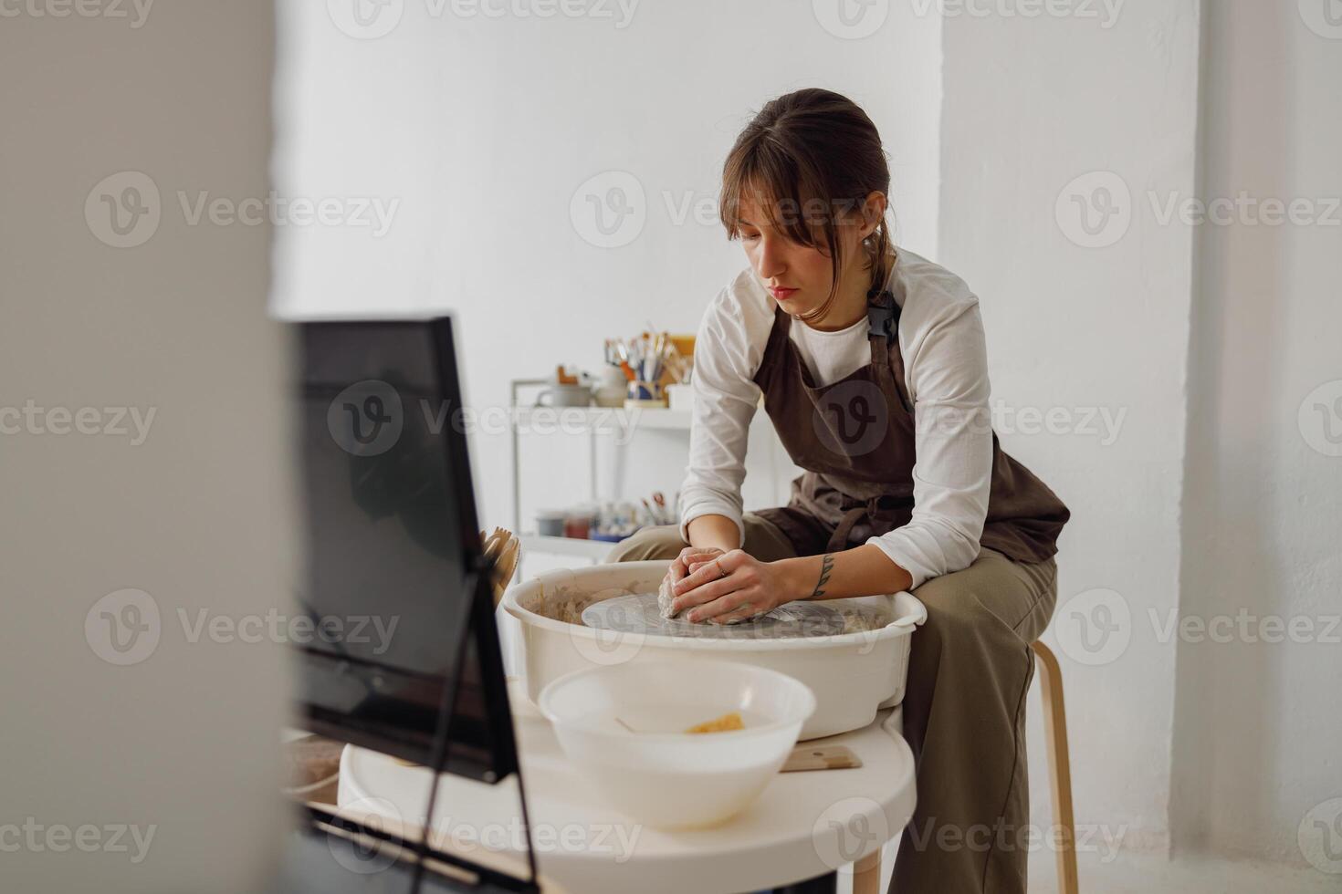 Professional female artisan shaping clay bowl in pottery studio. Ceramics art concept photo