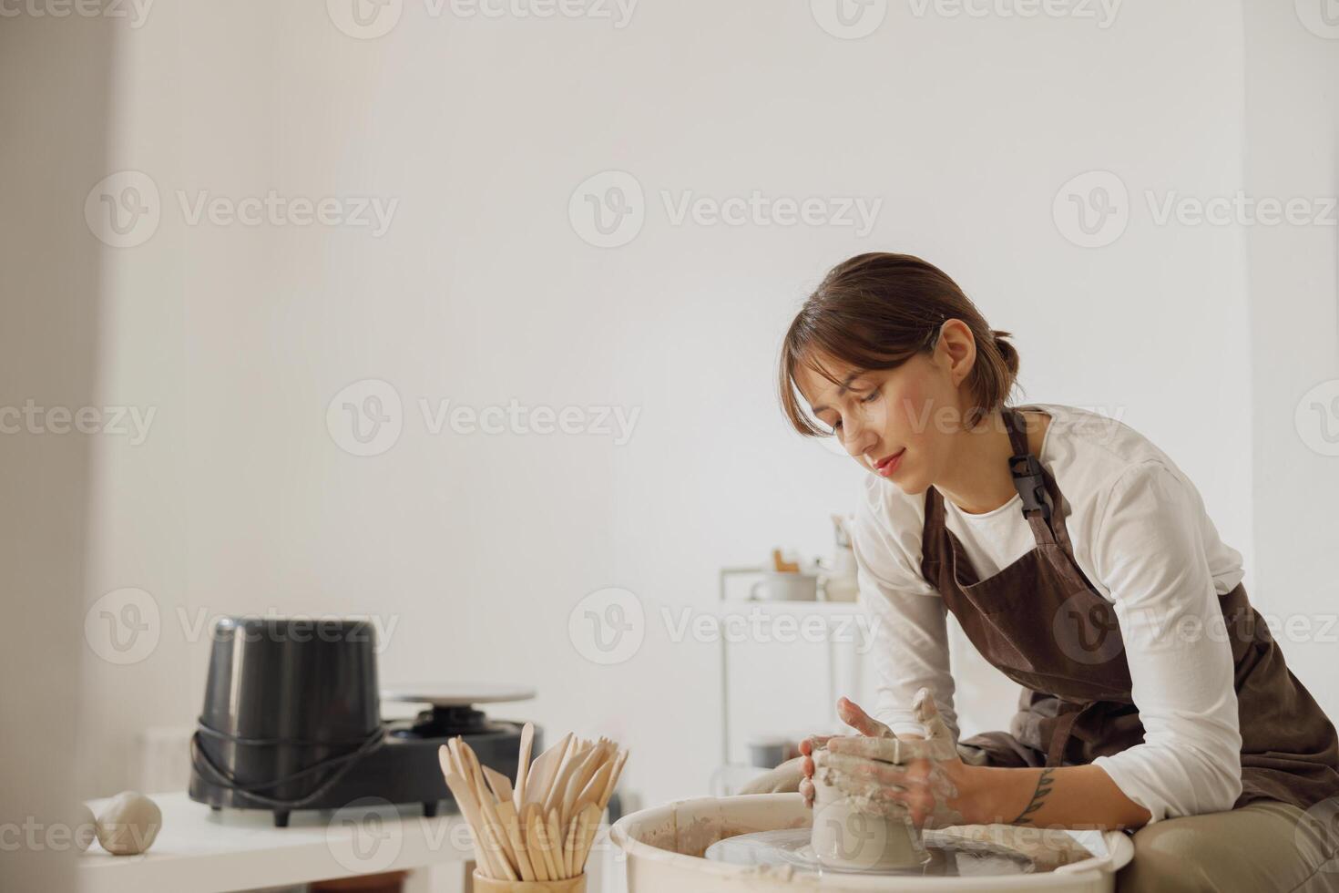 Professional female artisan shaping clay bowl in pottery studio. Ceramics art concept photo