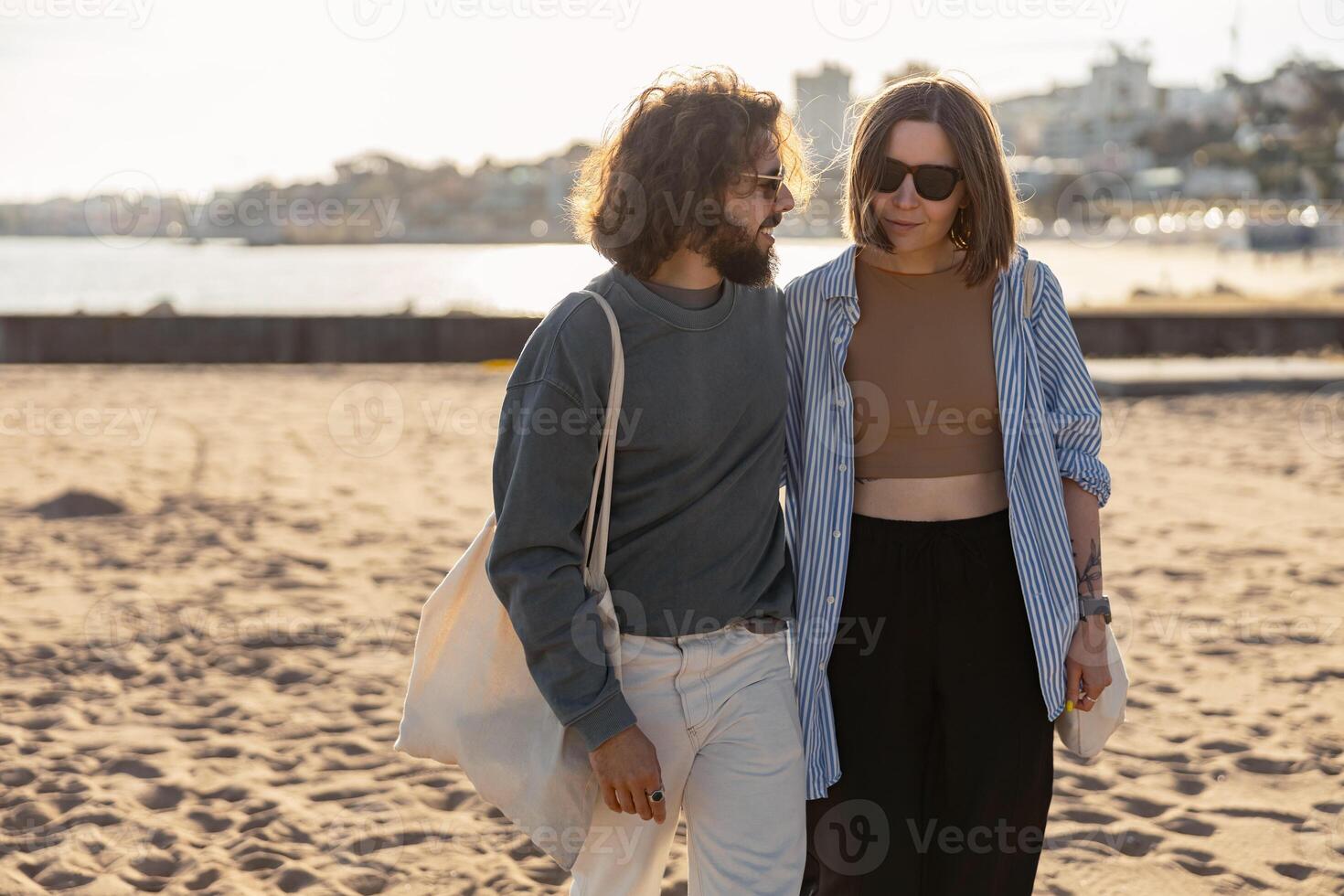 hermoso Pareja en amor abrazando mientras caminando a lo largo el playa en soleado día foto