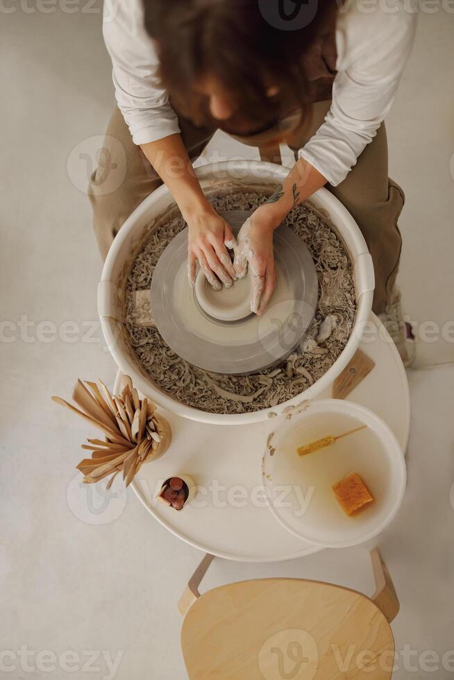 Close up of hands of professional potter molding pot shape on pottery wheel. Ceramics art concept photo