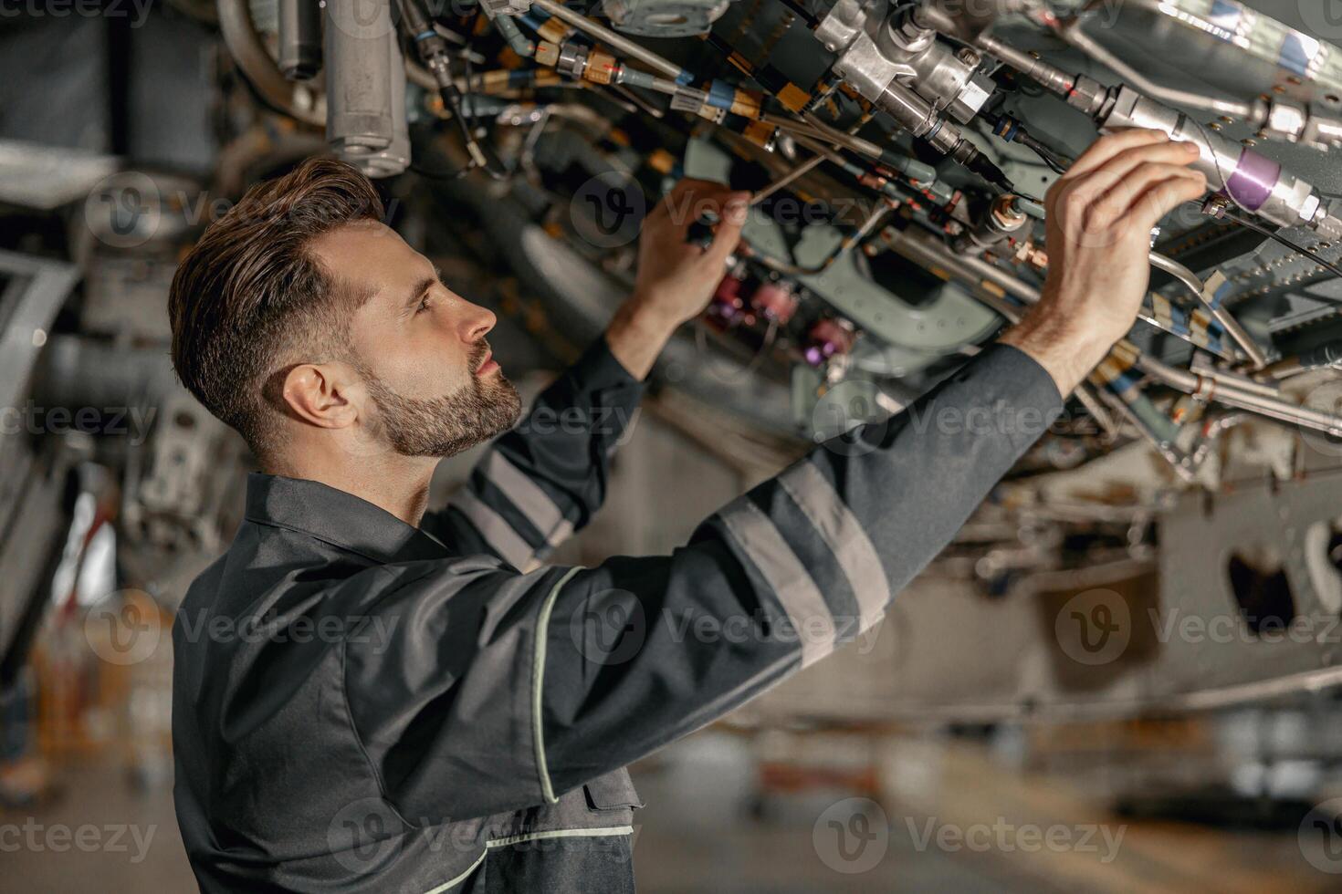 Male maintenance technician repairing airplane in hangar photo