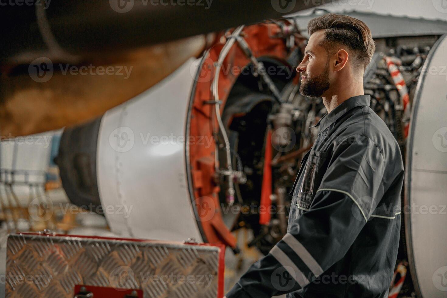 Bearded man aviation mechanic working in hangar photo