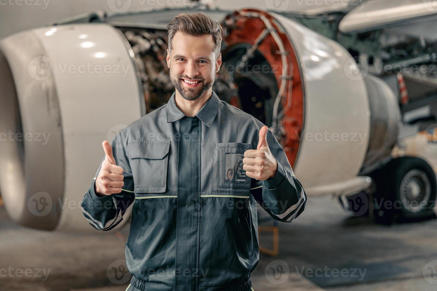 Joyful airline mechanic showing approval gesture in hangar photo