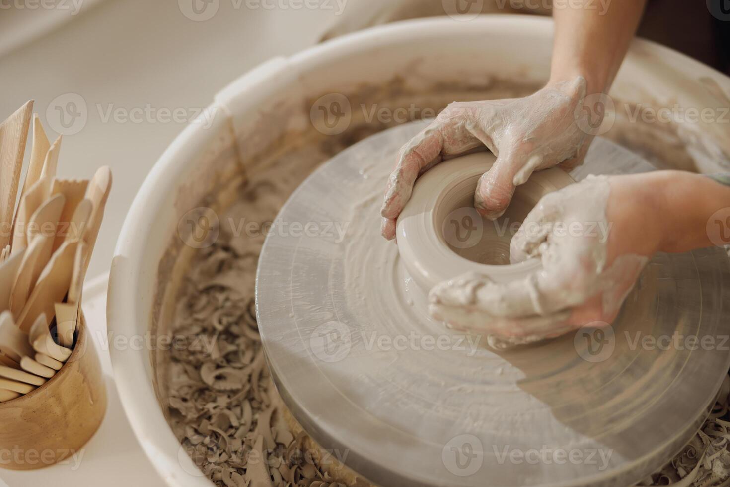 Close up of artisan's hands shaping clay bowl in pottery studio. Pottery art and creativity photo