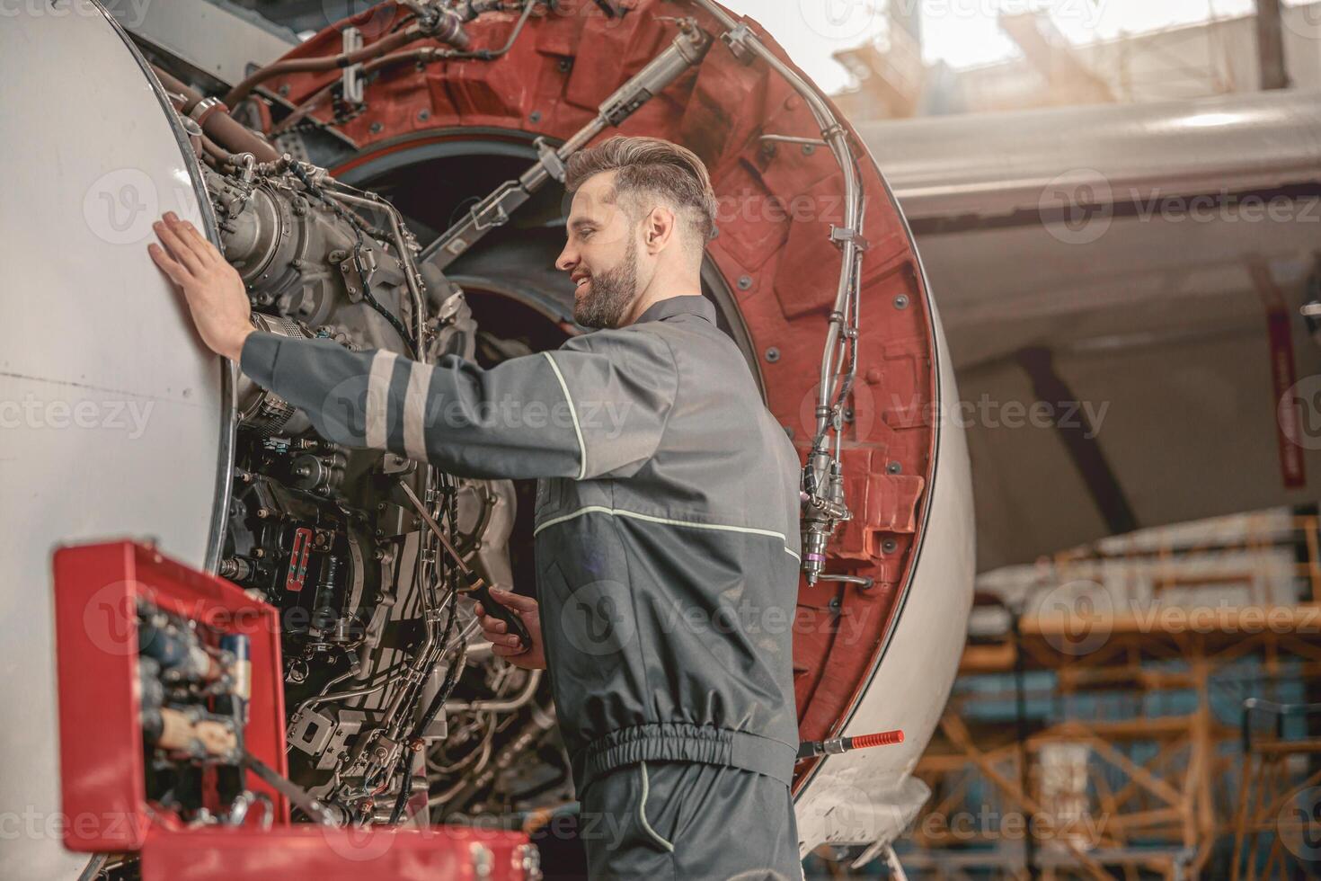 Joyful male mechanic repairing airplane in hangar photo