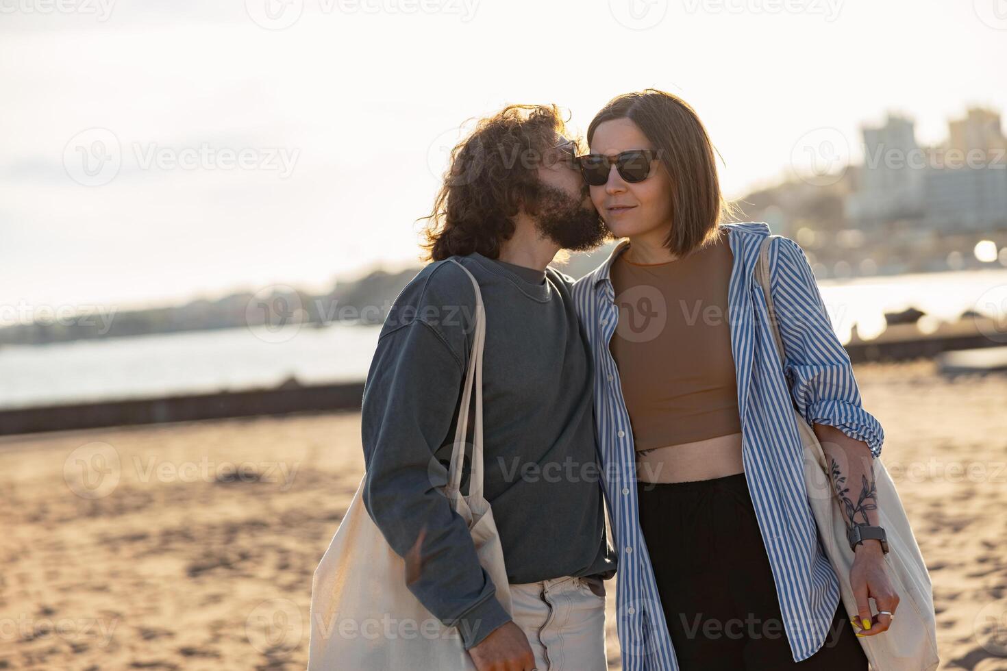 sonriente romántico Pareja en amor besos mientras caminando a través de el playa en puesta de sol foto