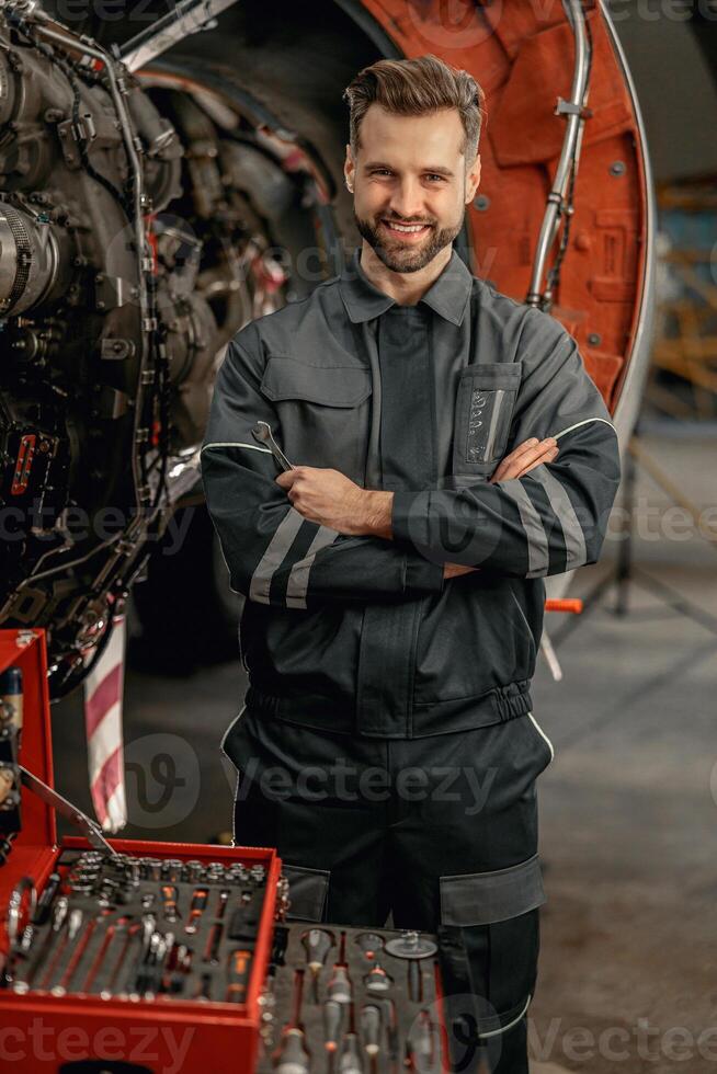 Cheerful aircraft mechanic standing near tool box in hangar photo