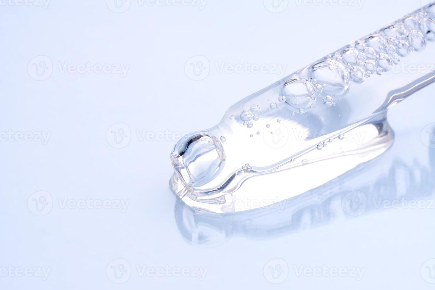 Liquid cool blue gel or serum on blue glass of microscope background photo