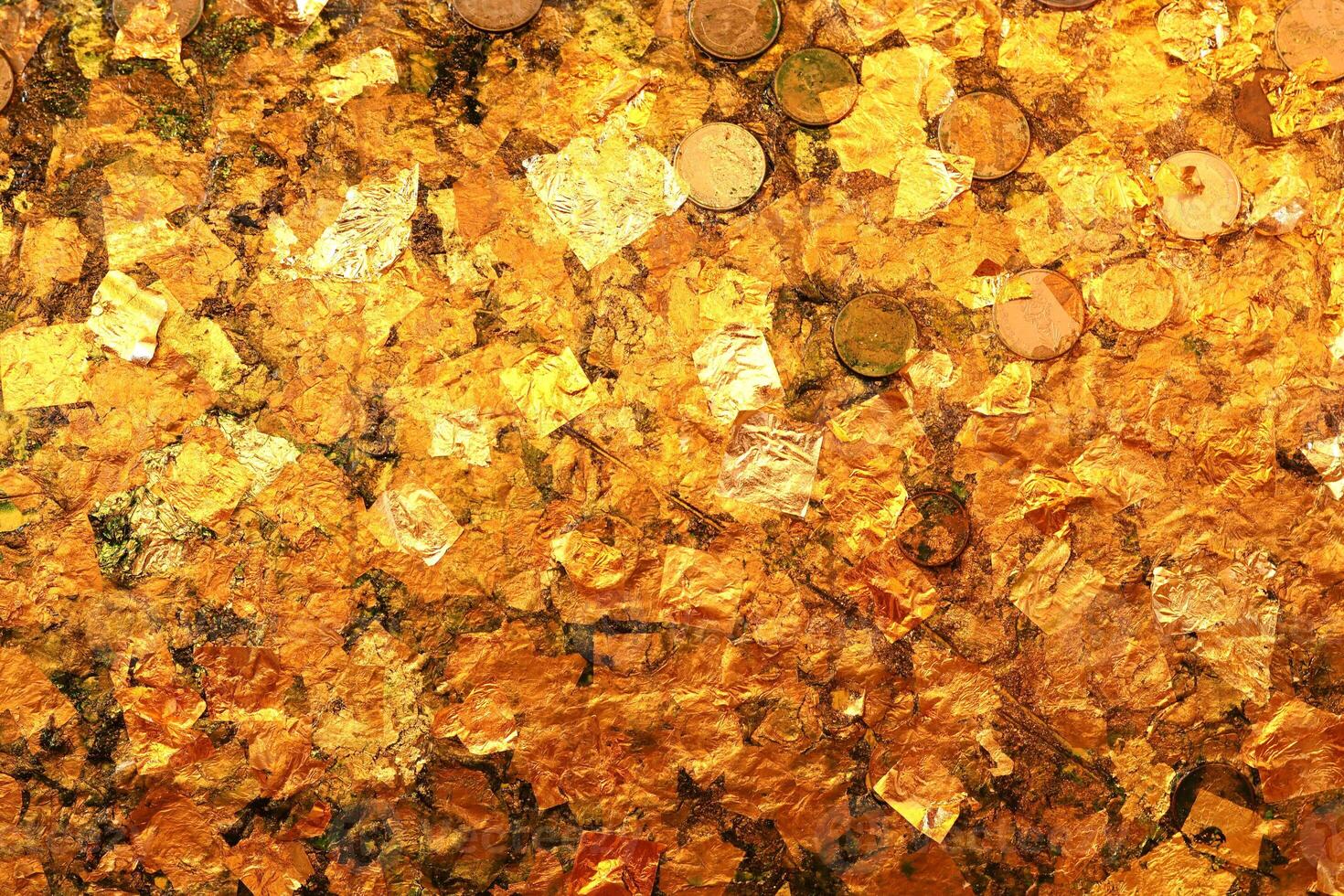 Gold leaf texture or background. Gold leaf and coin on buddha  statue. photo