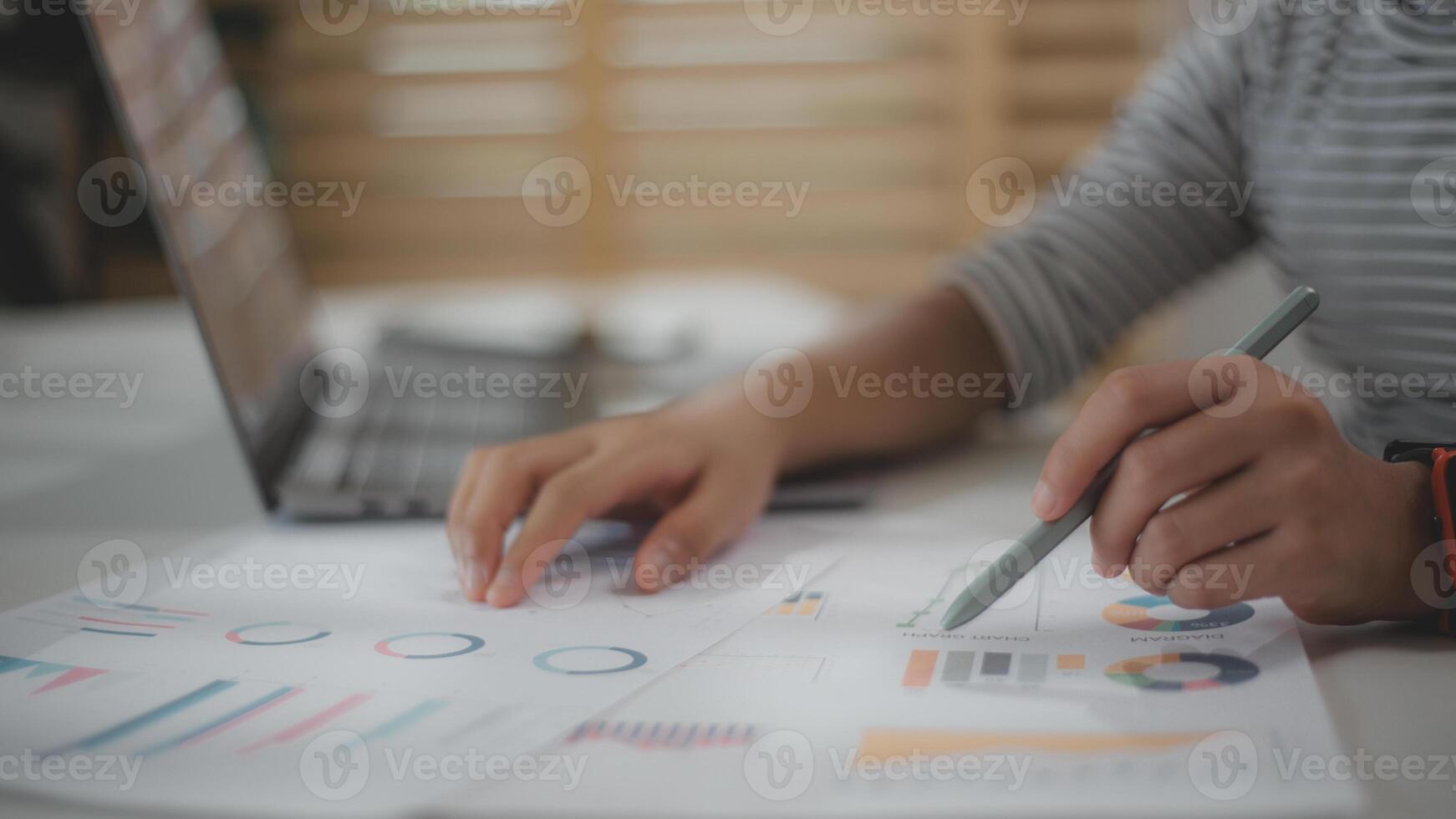 Close-up of businesswoman's hands checking company finances and earnings and budget with graph on the desk in the office. photo