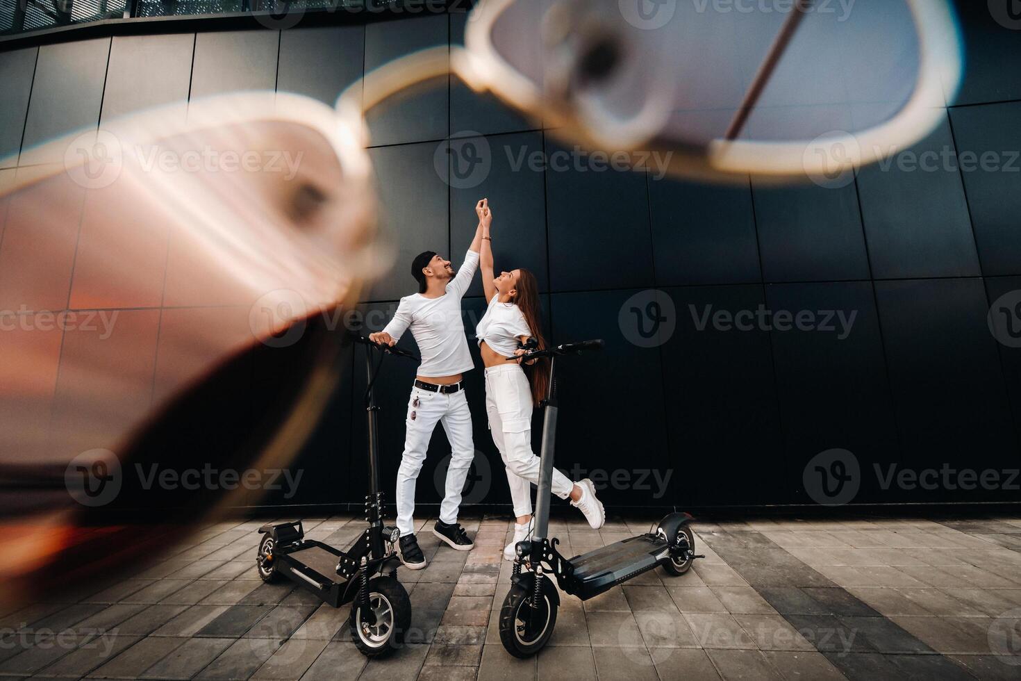 A girl and a guy are walking on electric scooters around the city, a couple in love on scooters. photo