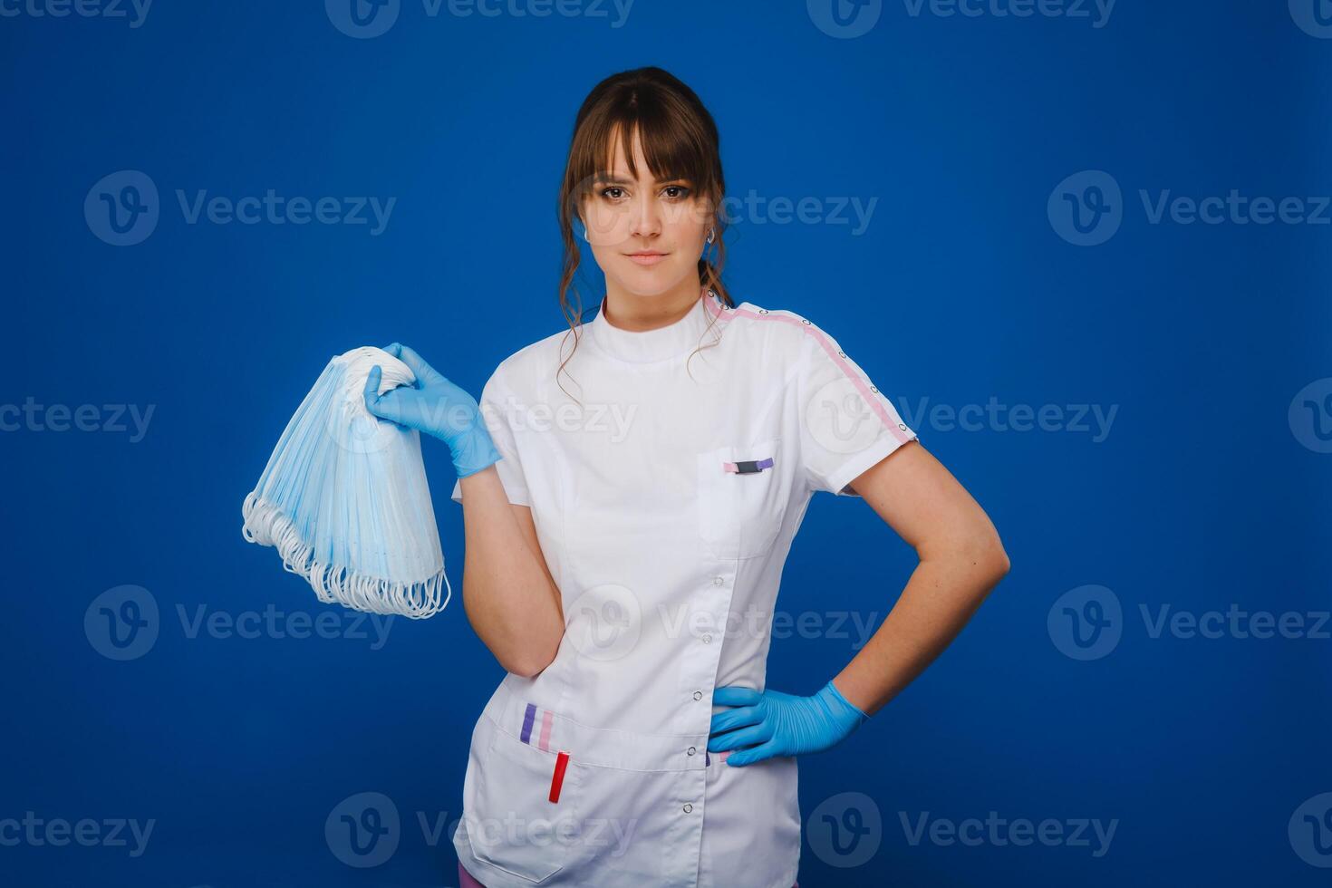 the doctor is holding a bunch of medical masks stacked together on a blue isolated background photo