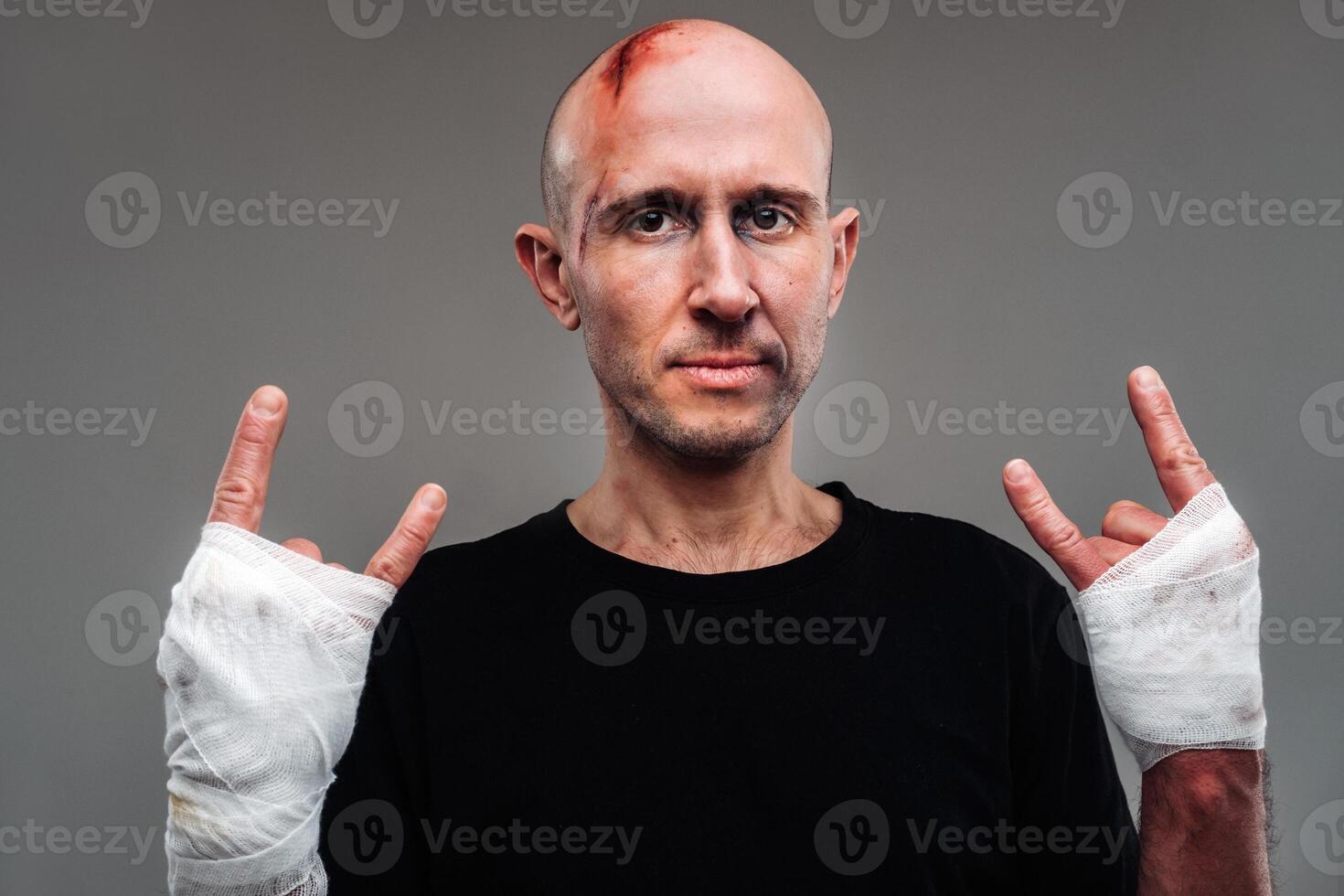 On a gray background stands a battered man in a black T-shirt With his hands wrapped up photo