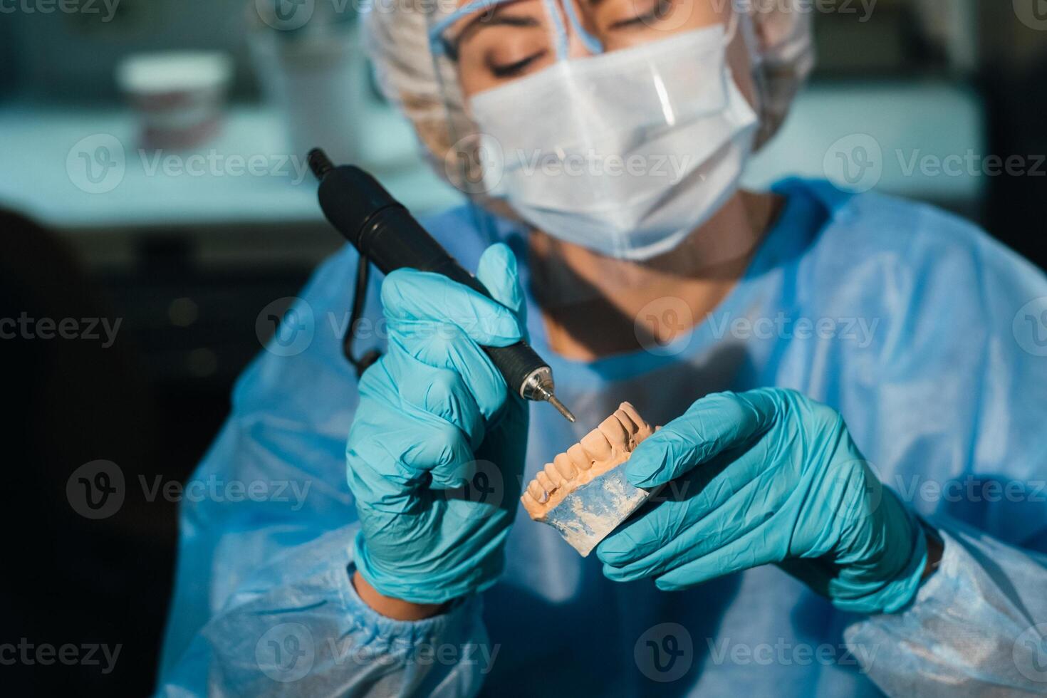 un enmascarado y enguantado dental técnico trabajos en un protésico diente en su laboratorio foto