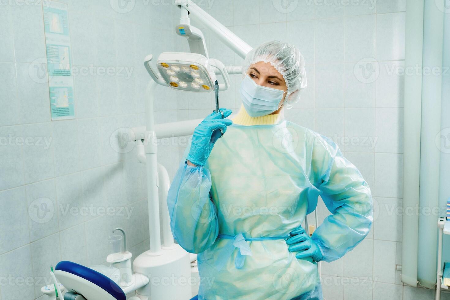 A masked dentist holds an injection syringe for a patient in the office photo