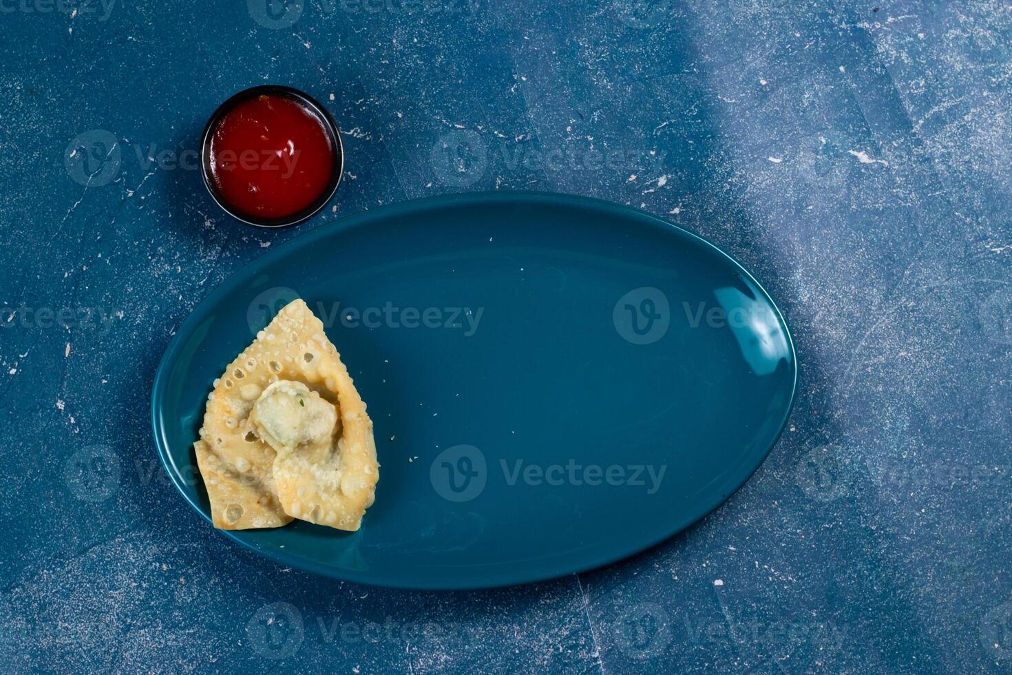 Crispy fried wonthon dim sum wraps with tomato sauce served in a dish isolaed on table top view photo