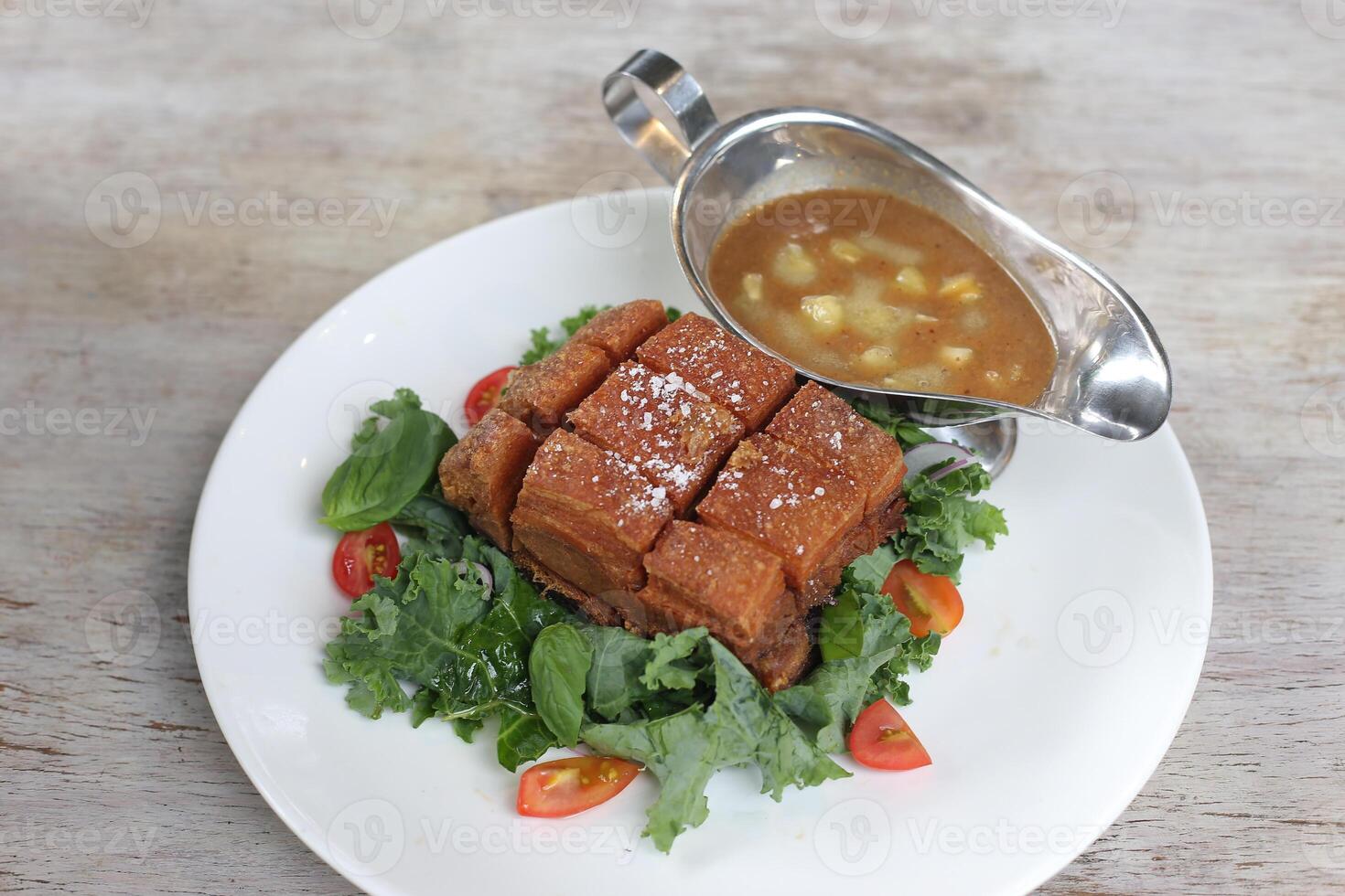 Giant Pork Belly Lechon Kawali with sauce served in a dish isolated on grey background side view photo