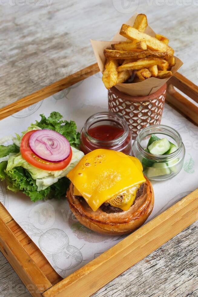 Char Grlled US Beef Cheese burger with salad, wedges and tomato sauce served in a serving board side view photo