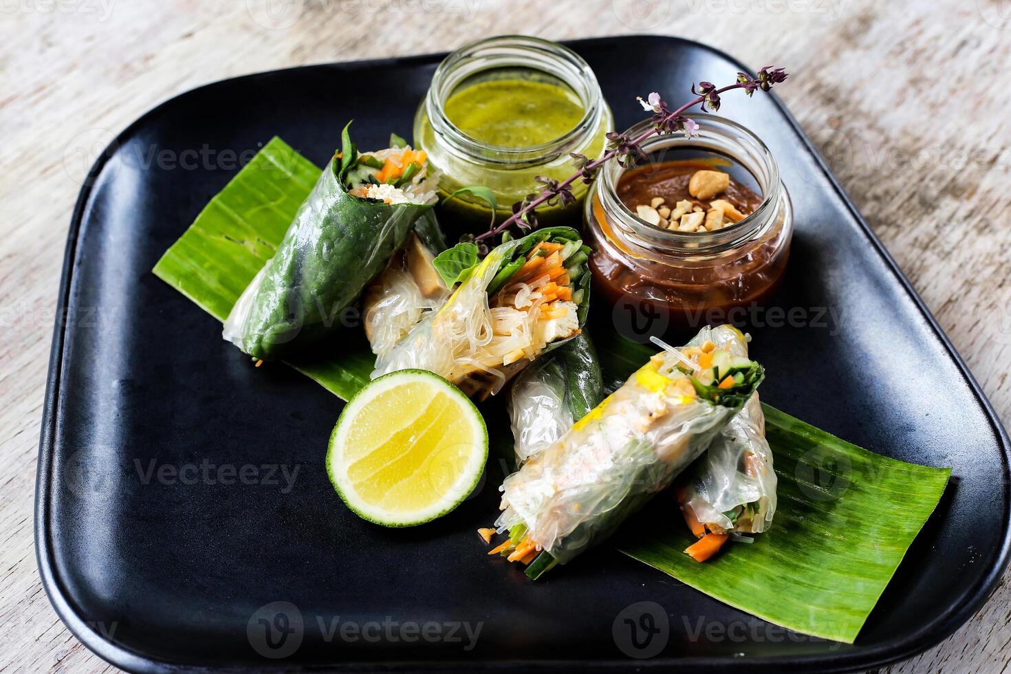 Fresh Spring Rolls with chilli sauce and lime served in a dish isolated on grey background side view of snacks photo