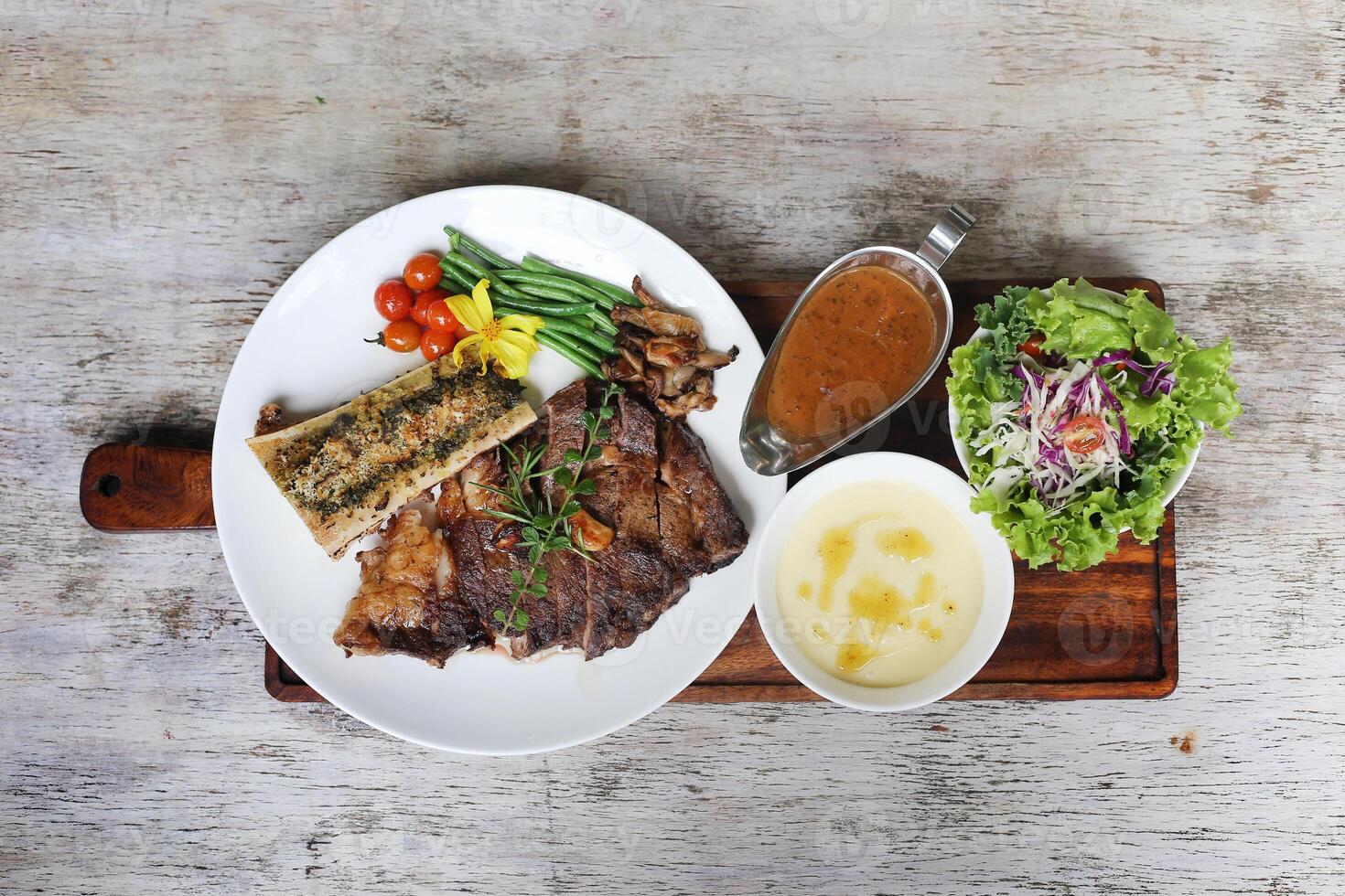 US Black Angus Rib Eye Steak with chilli sauce and salad served in a dish isolated on grey background side view photo