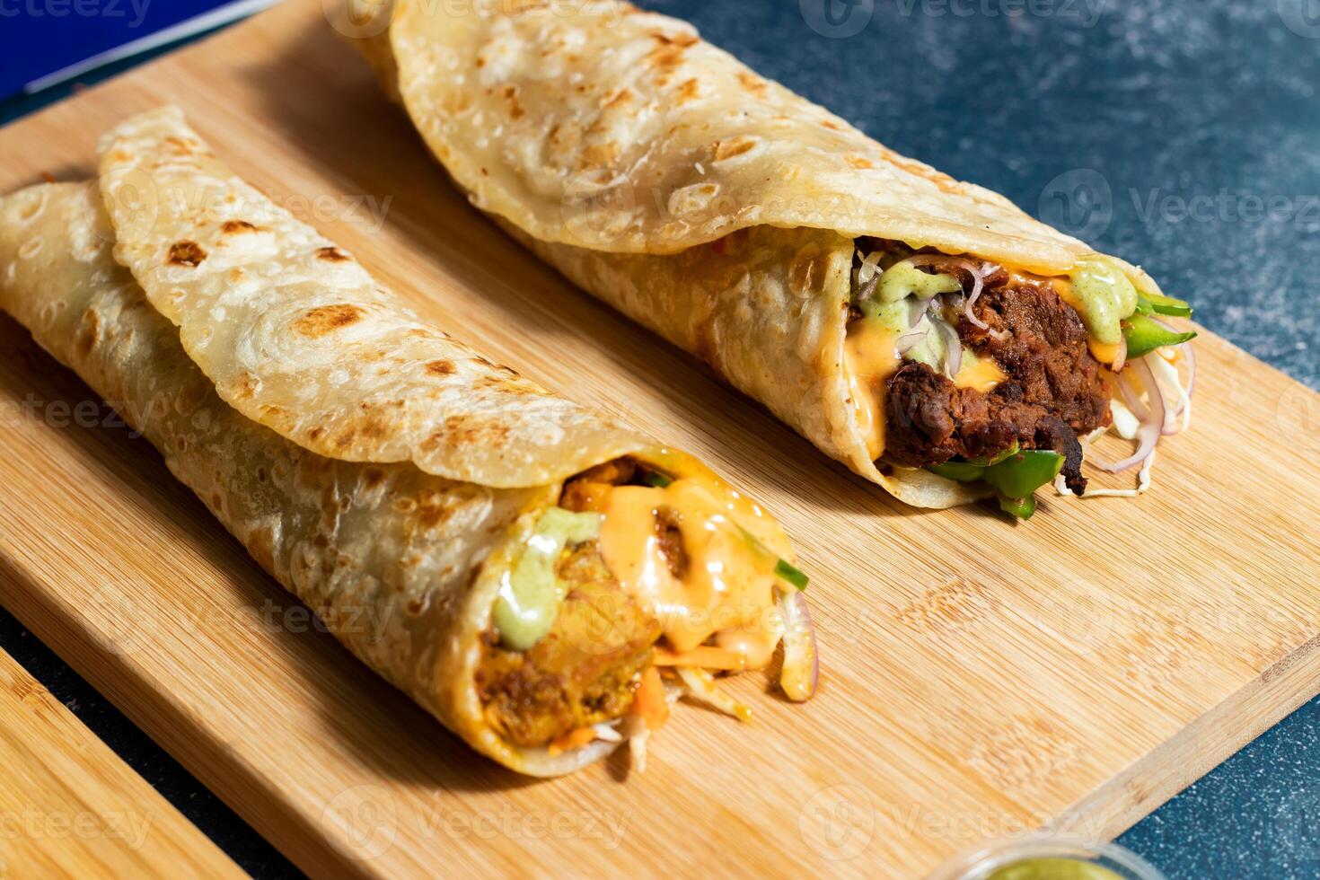 Beef Seekh Kebab Wrap, Chole Chicken shawarma Wrap with salad dip and sauce isolated wooden board side view of fastfood photo