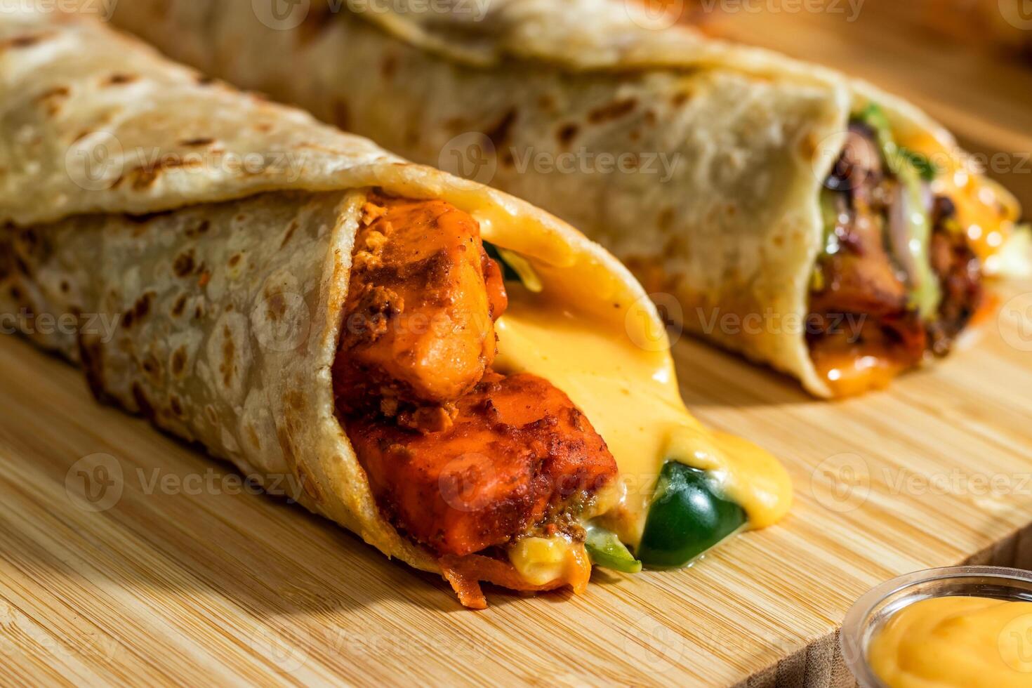 Melt Cheese Paneer Wrap, Chicken Afghani Kebab shawarma Wrap with salad dip and sauce isolated wooden board side view of fastfood photo