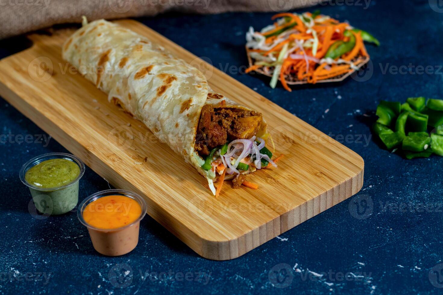 Paneer Tikka shawarma Wrap with salad dip and sauce isolated wooden board side view of fastfood photo