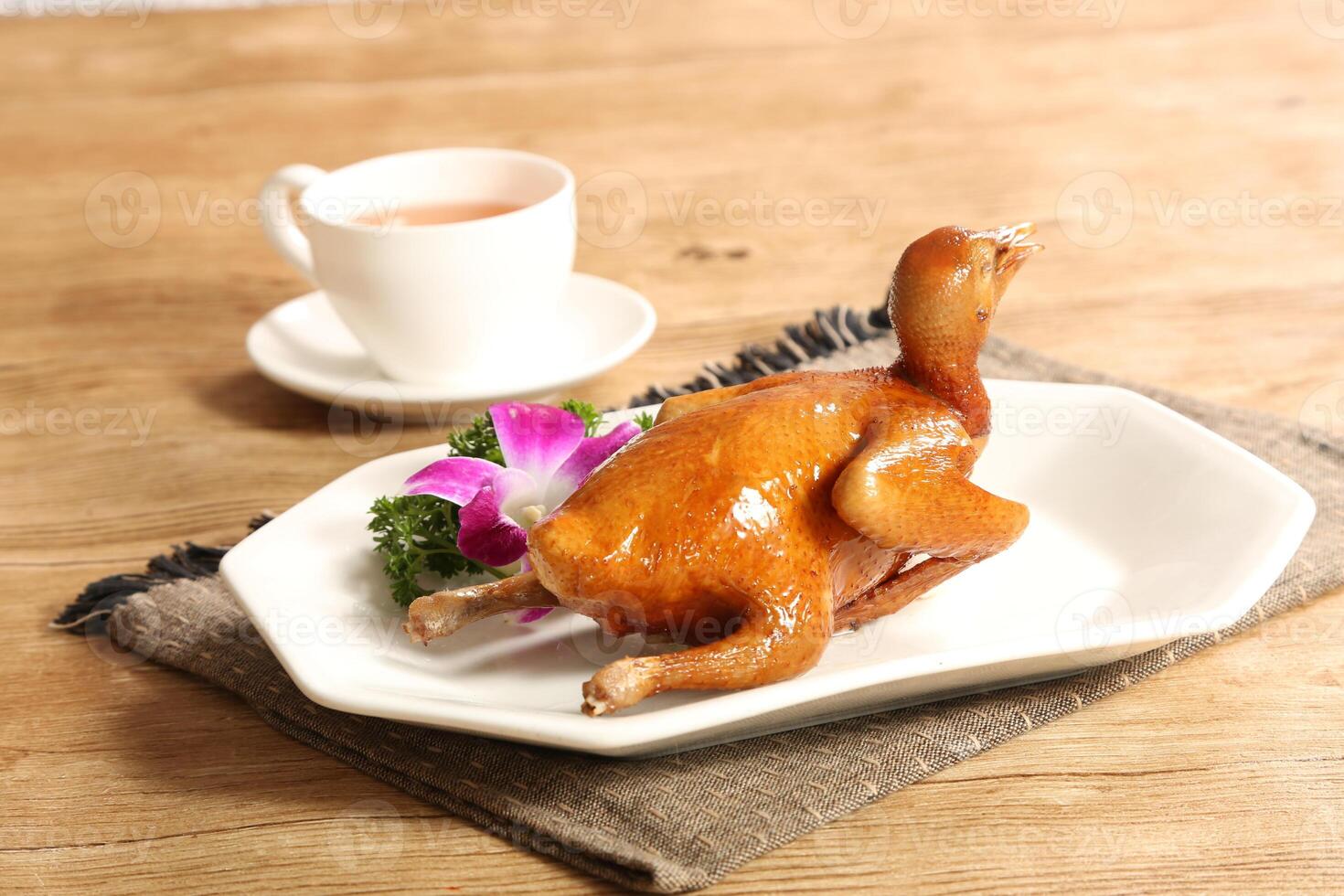 Traditional Cantonese grilled squab or pigeon in a dish isolated on grey background side view of Hong kong food photo