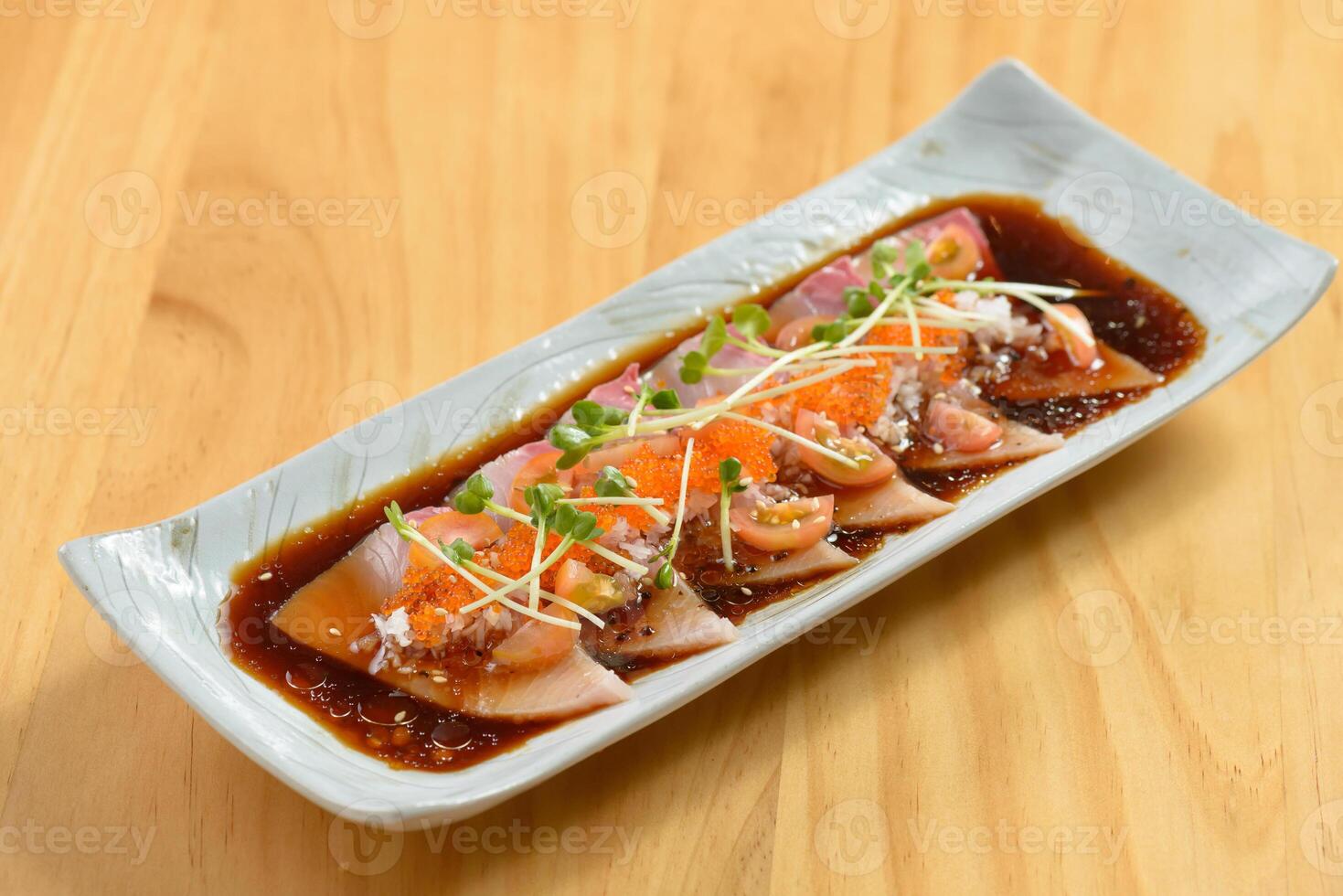 Fish Hamachi Carpaccio with chili sauce in a white tray on wooden background top view of japanese food photo