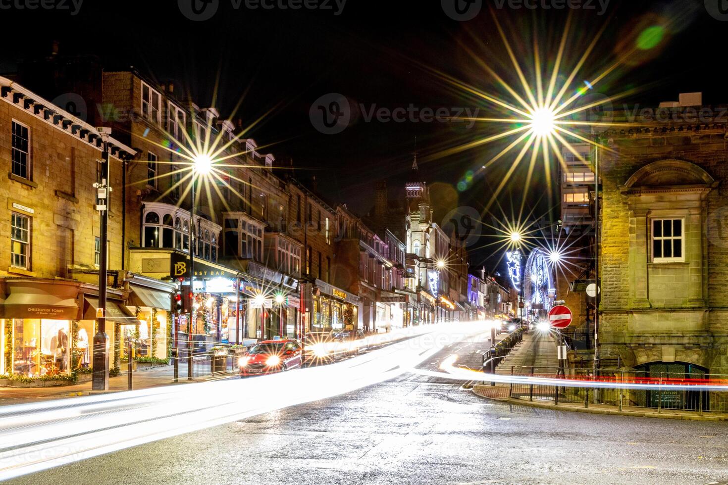 Nighttime city street with illuminated buildings and light trails from moving vehicles in Harrogate, North Yorkshire, UK. photo