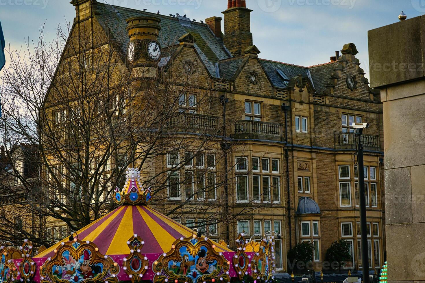 Vintage building with clock tower behind colorful carousel in urban setting at dusk in Harrogate, North Yorkshire, UK. photo