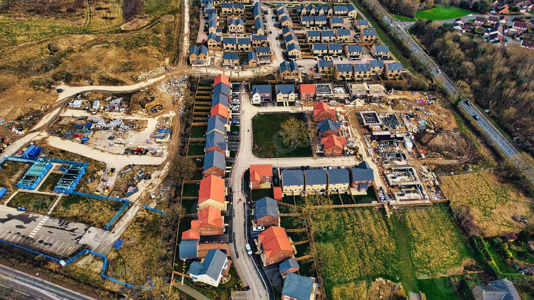 Aerial view of a suburban development with rows of houses, showing construction areas and completed homes with red roofs in Harrogate, North Yorkshire. photo