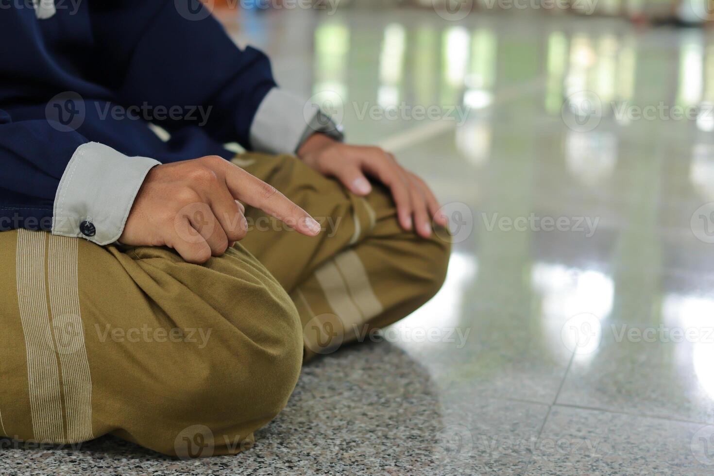 Portrait of religious Asian man in muslim shirt praying and doing salat or sholat in mosque photo