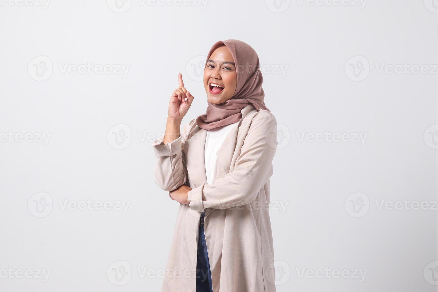 retrato de emocionado asiático hijab mujer en casual traje señalando arriba su dedo índice y recordando alguna cosa a hacer. mujer de negocios concepto. aislado imagen en blanco antecedentes foto